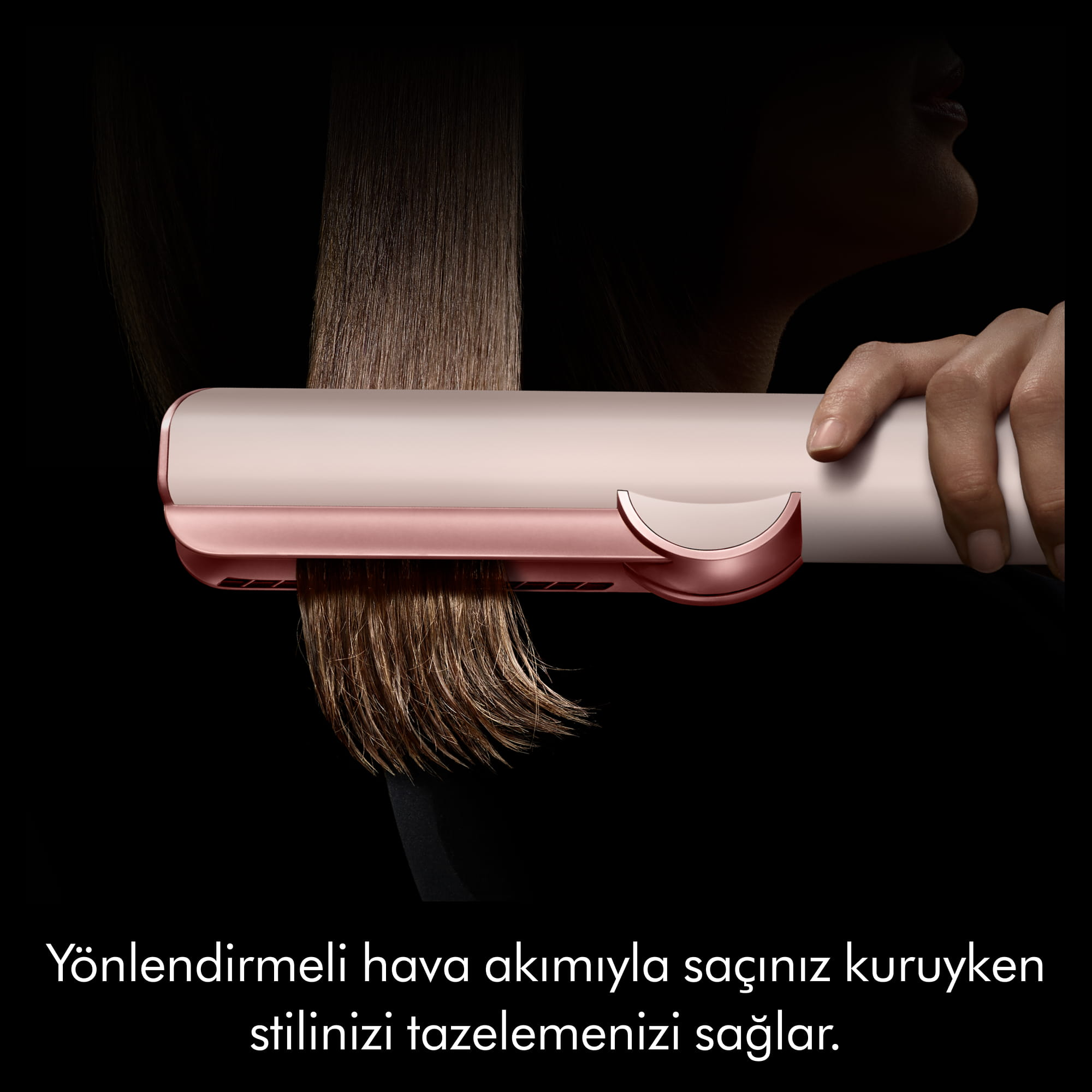 Bir el, yönlendirmeli hava akımıyla kuru saçı şekillendiren pembe altın saç şekillendiriciyi tutuyor.