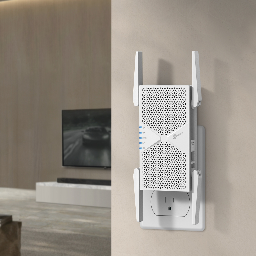 Egy fehér, négyantennás Wi-Fi jelismétlő van bedugva egy fali aljzatba egy modern nappaliban.