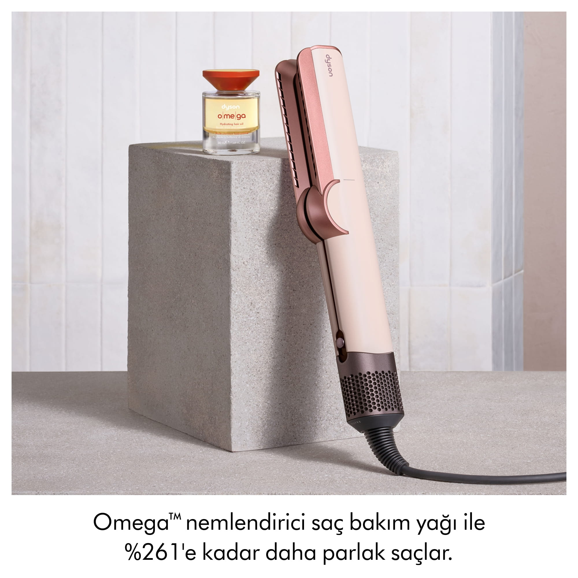 Beyaz duvar önündeki beton blok üzerinde Dyson saç şekillendirici ve saç bakım yağı.