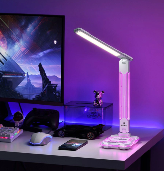 Biała lampka biurkowa LED z kolorowymi światłami stoi na biurku obok monitora i klawiatury.