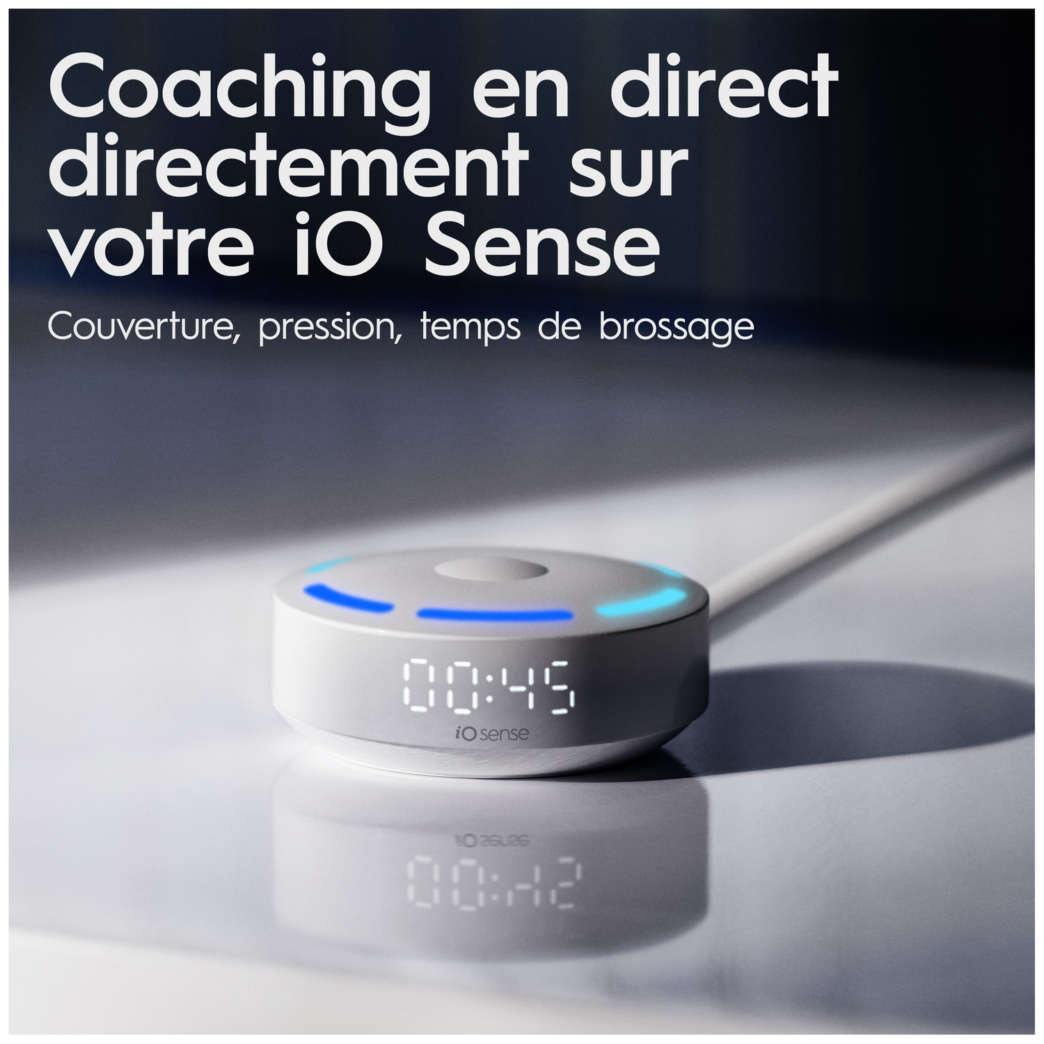 Un appareil iO Sense blanc avec lumière bleue et affichage numérique sur une surface réfléchissante avec du texte.