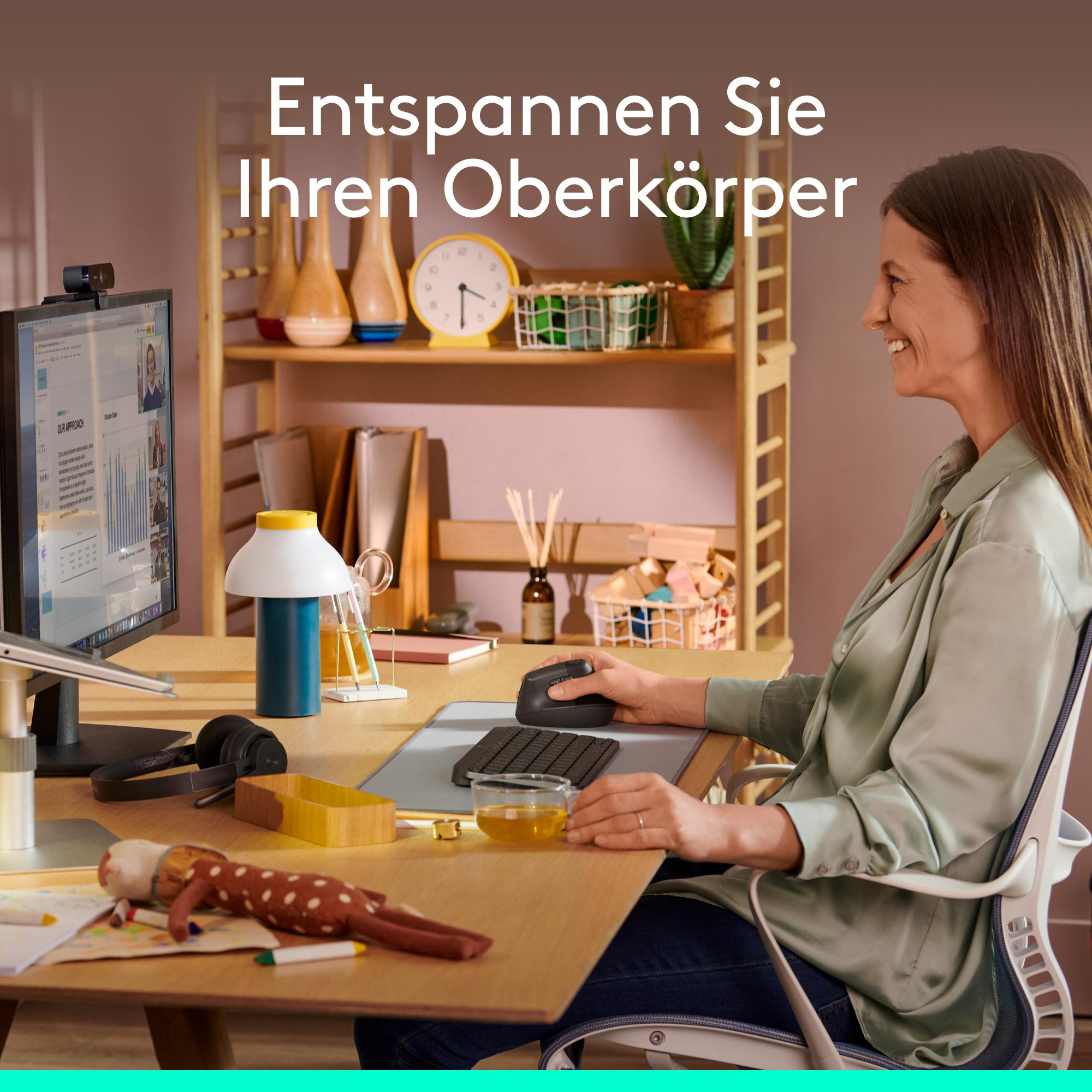 Eine Frau sitzt an einem Holztisch mit Computer, Tastatur und Maus. Im Hintergrund steht ein Regal.