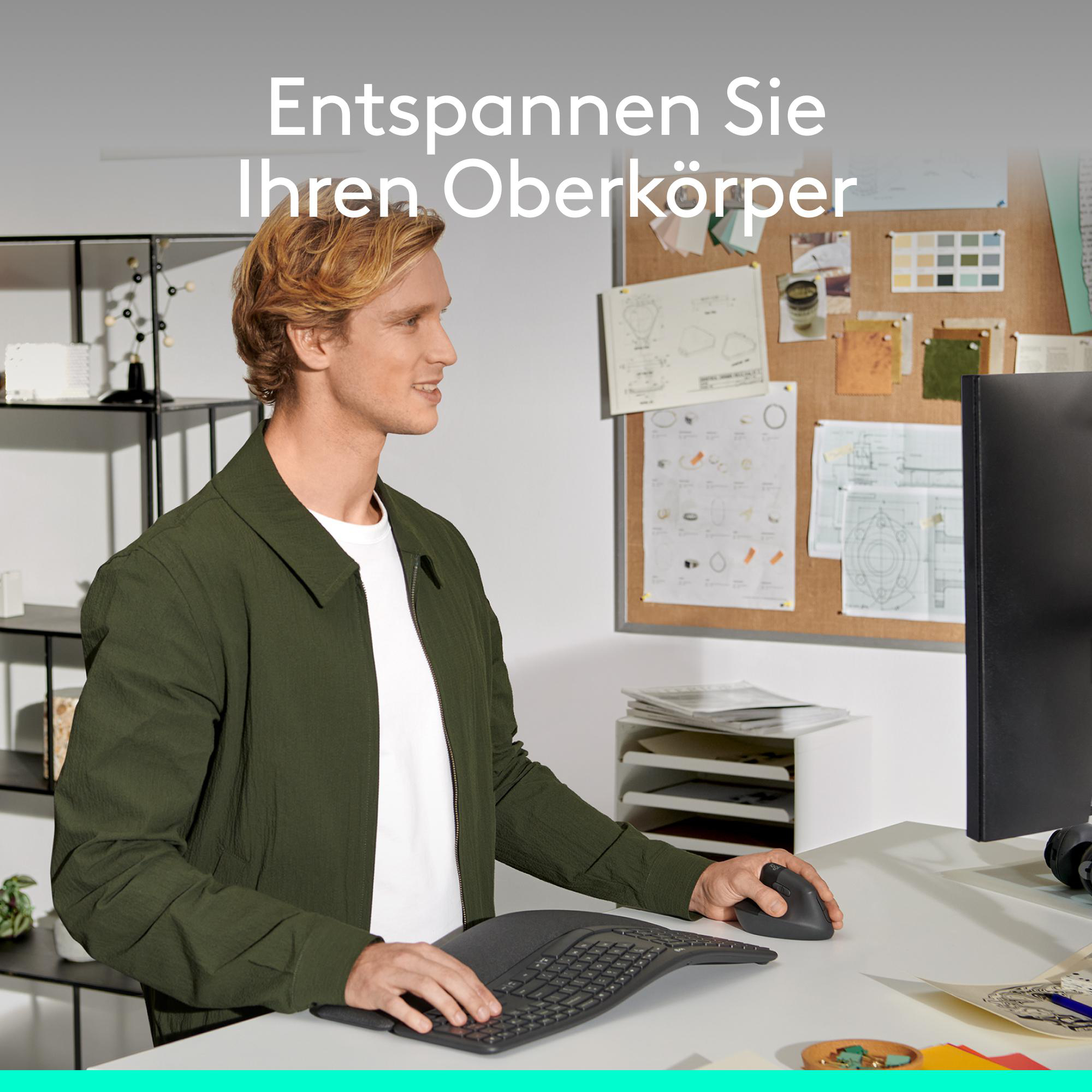 Ein blondhaariger Mann arbeitet an einem Schreibtisch mit ergonomischer Tastatur und vertikaler Maus.