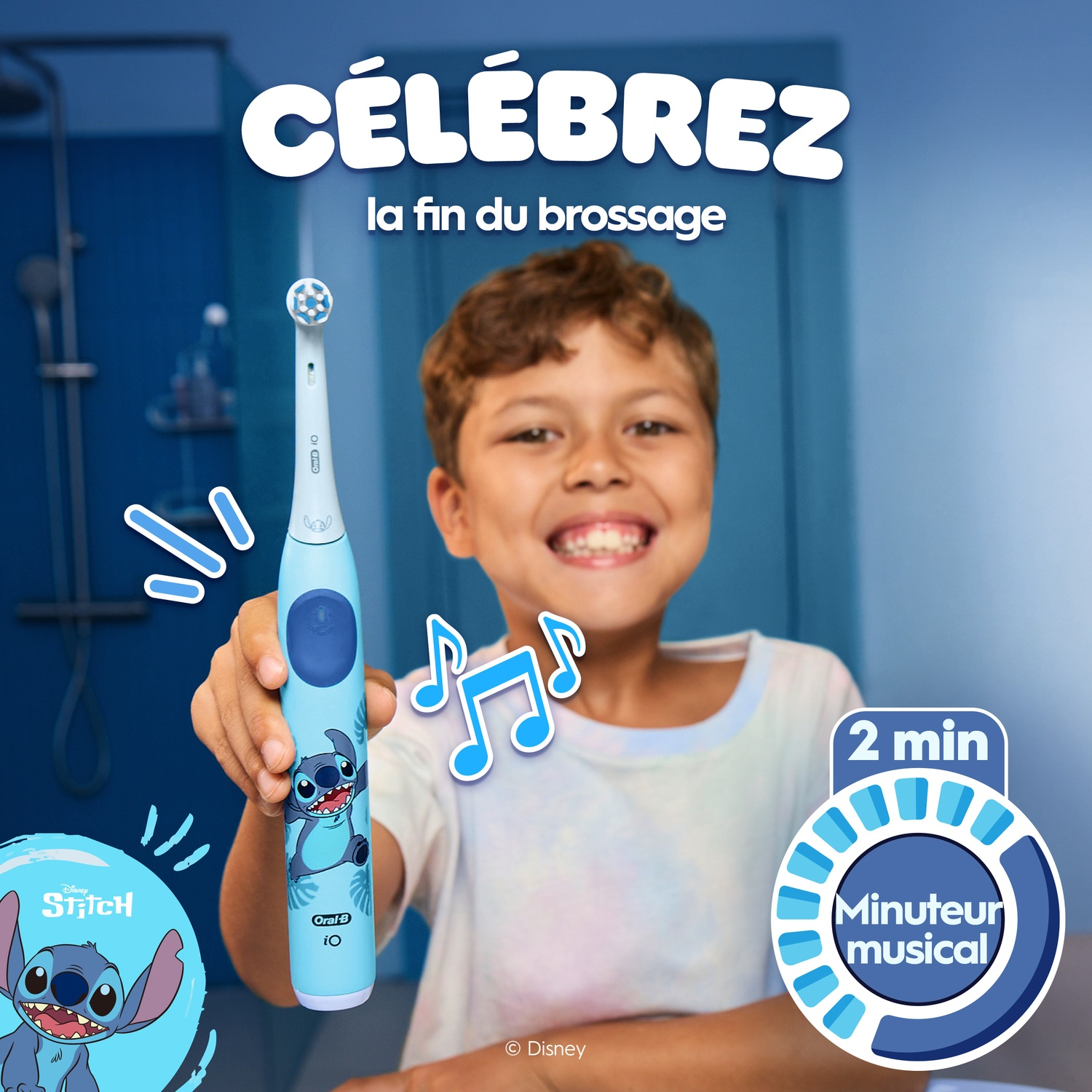 Un garçon souriant tenant une brosse à dents électrique Oral-B Stitch bleu clair dans une salle de bains.