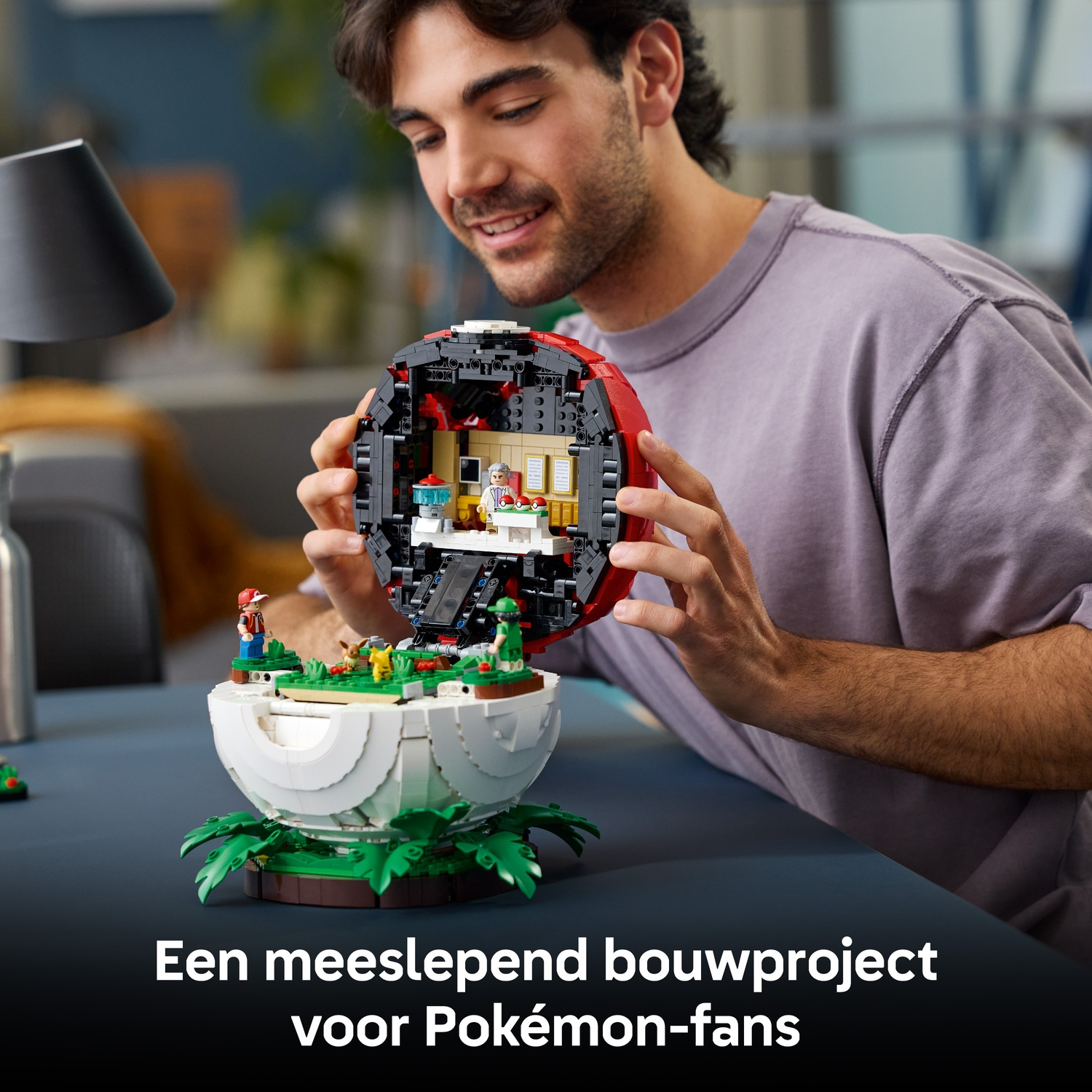 Een man bouwt een open Lego Pokéball-model met miniatuurfiguren binnenin.