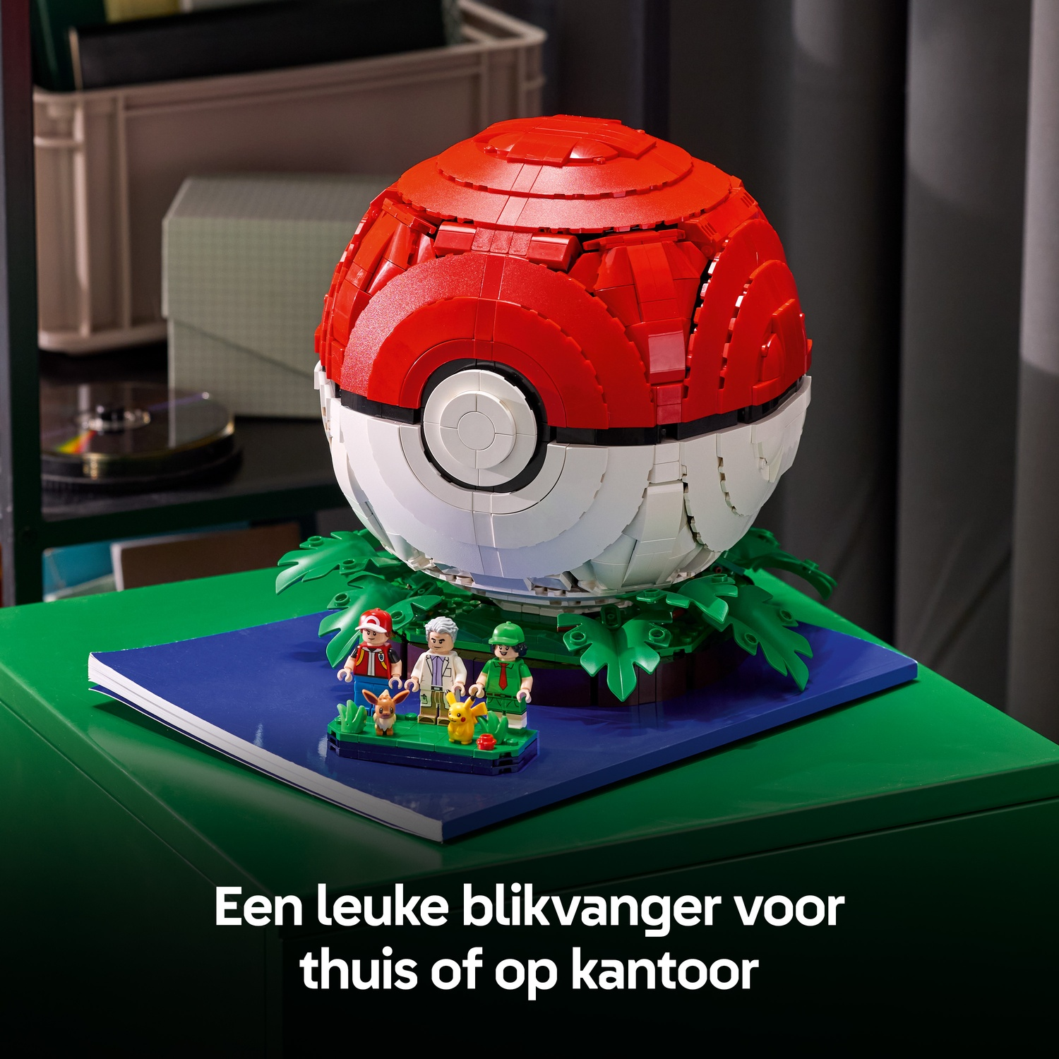 Een grote rode en witte Lego Pokébal met kleine minifiguren ervoor op een groene tafel.