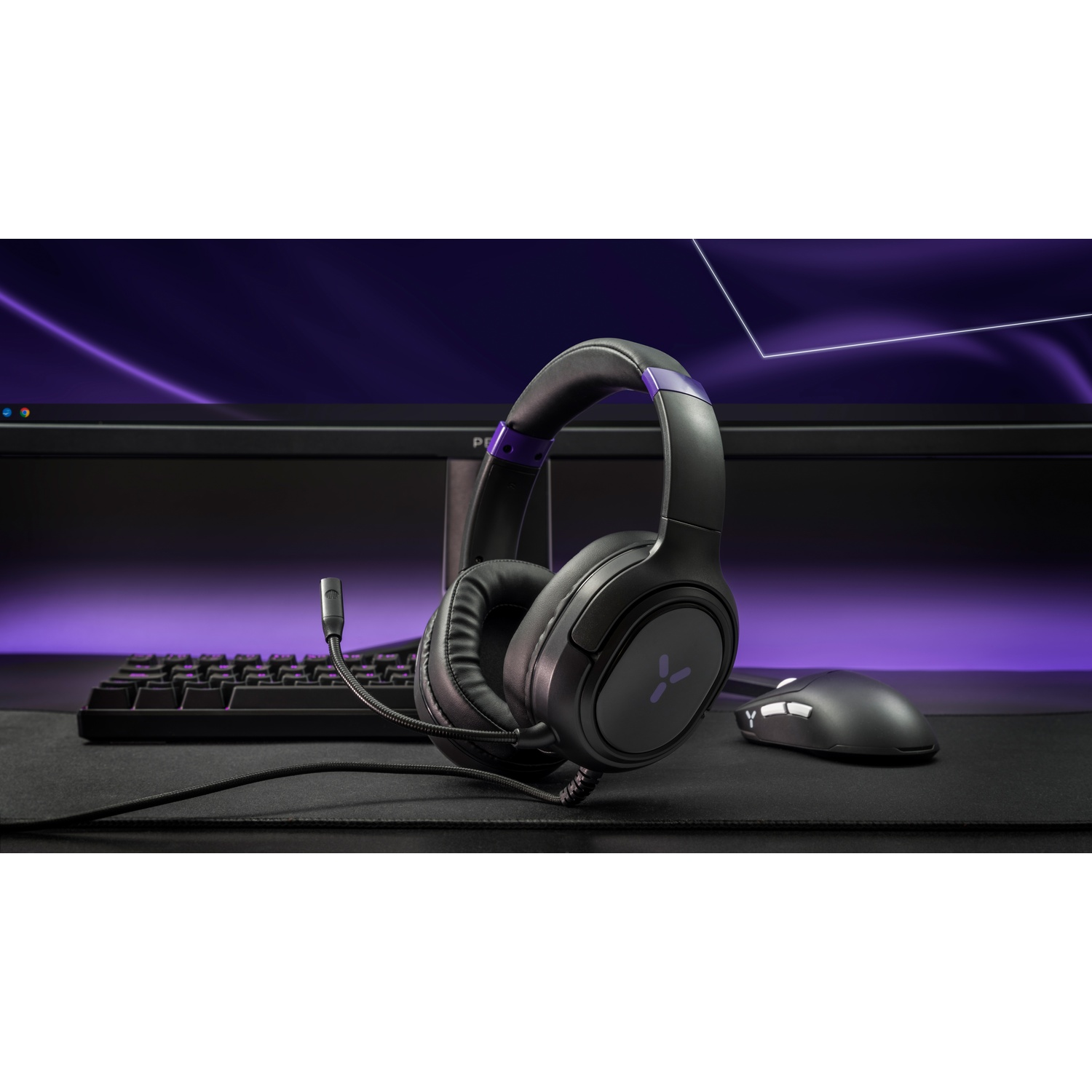 Black gaming headset with a mic on a desk in front of a purple keyboard and monitor.