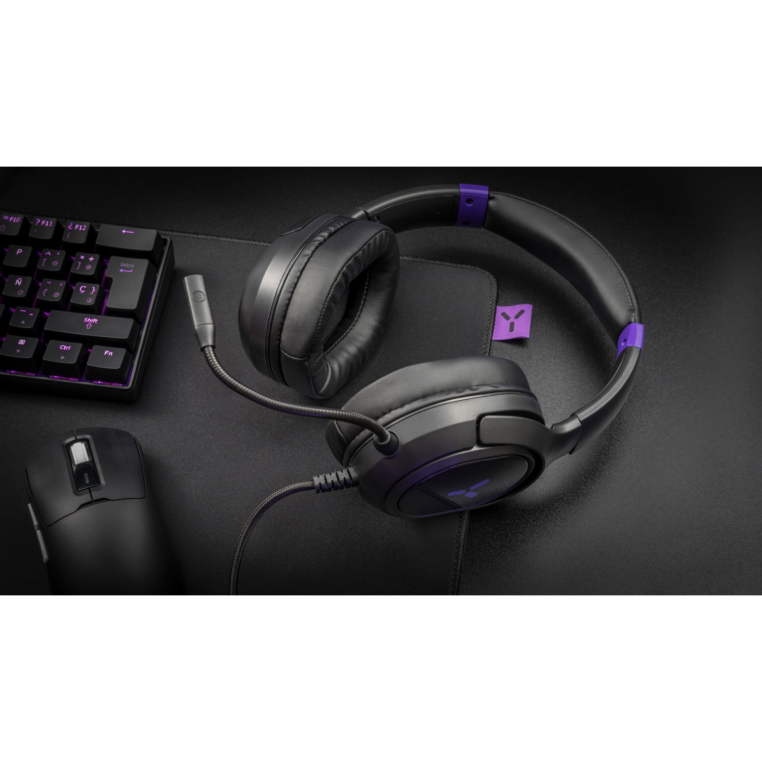 Black gaming headset with microphone, keyboard, and mouse on a mousepad.