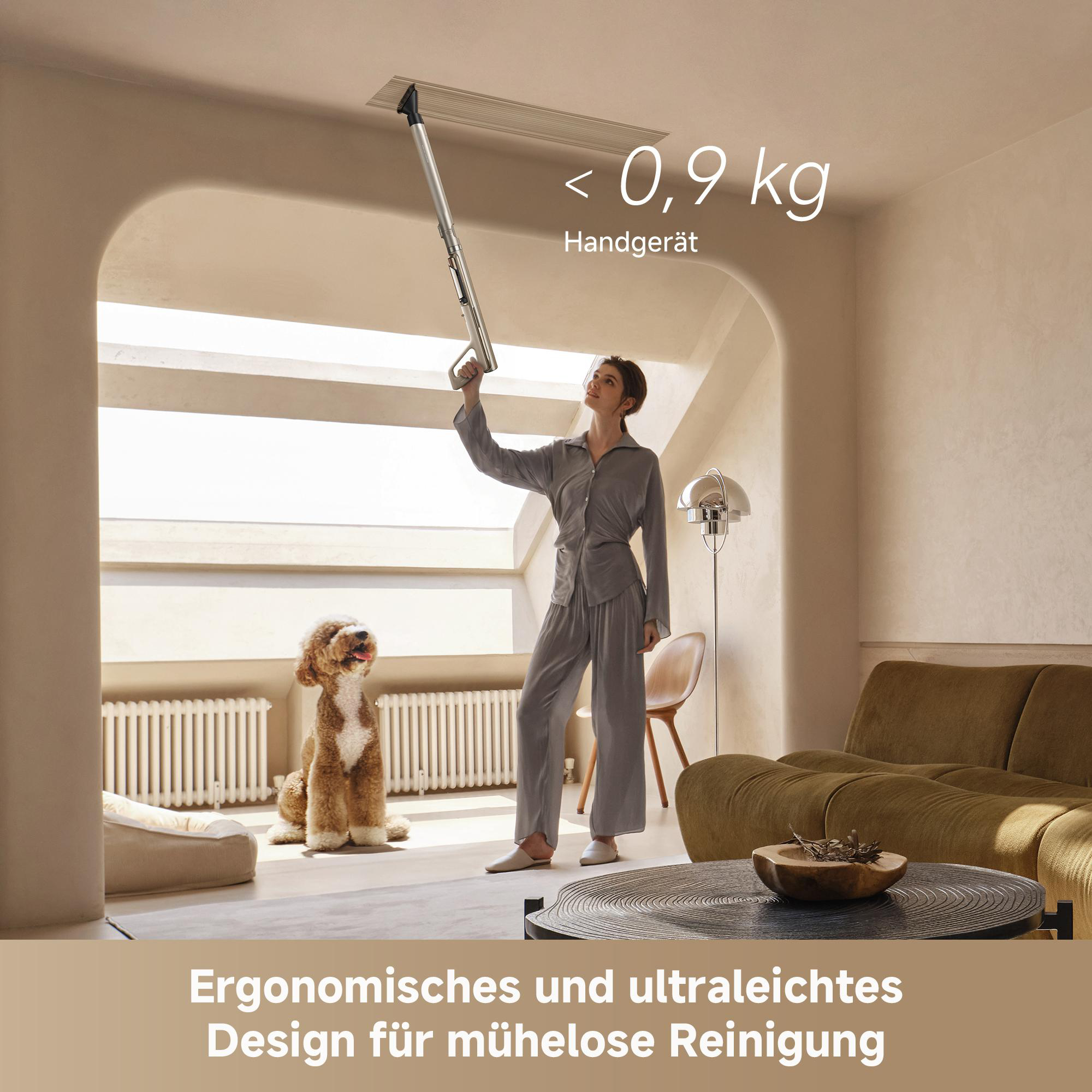 Eine Frau in Pyjamas saugt die Decke mit einem leichten Handstaubsauger, während ihr Hund zusieht.