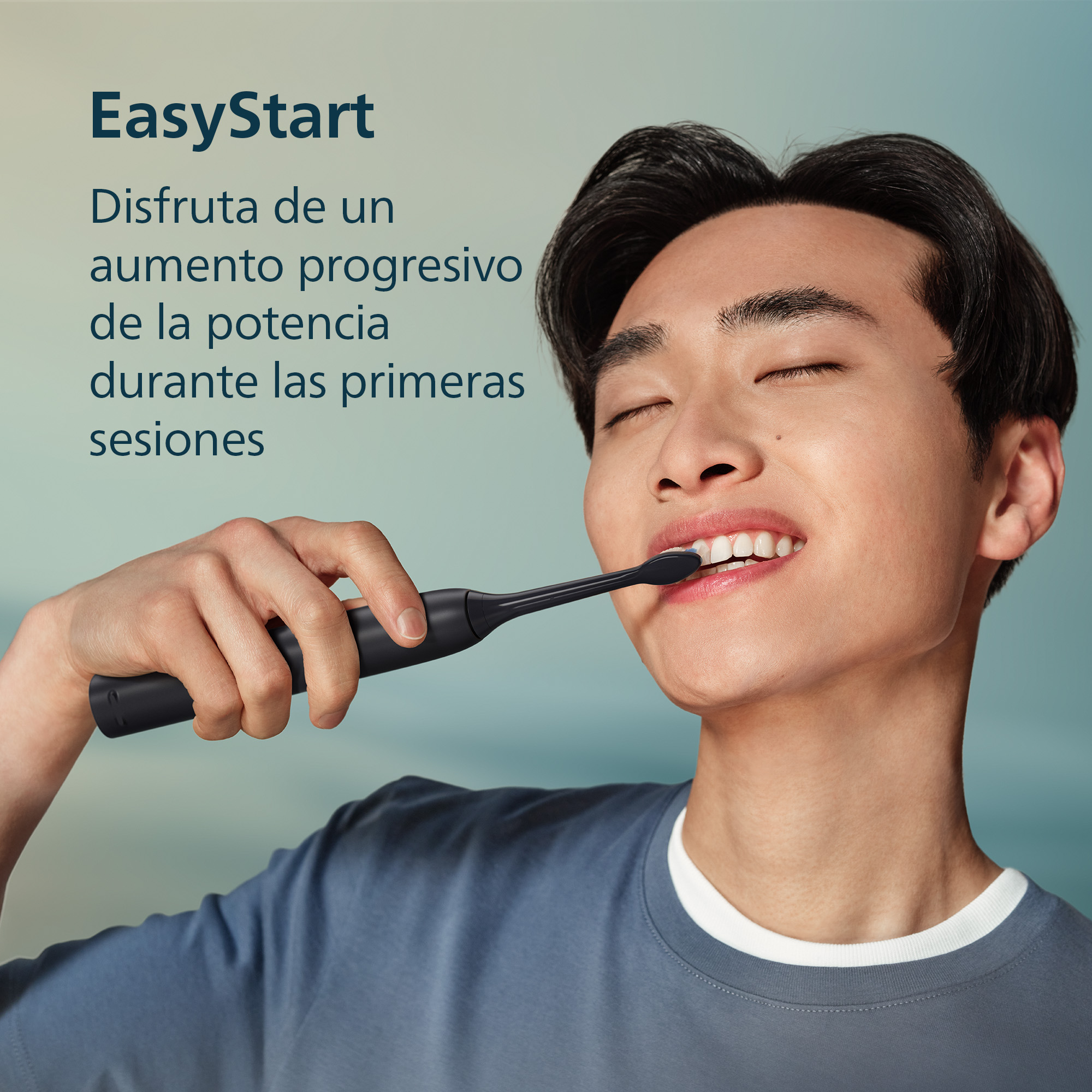 Un joven sonríe feliz mientras se cepilla los dientes con un cepillo eléctrico negro.