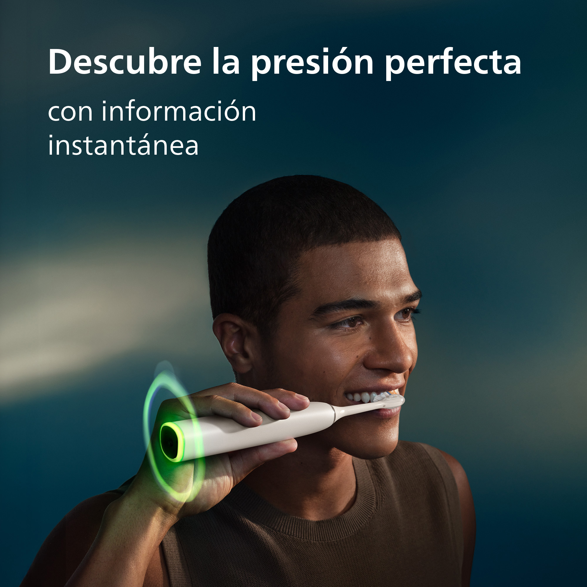 Un hombre sonriendo y cepillándose los dientes con un cepillo eléctrico con luz verde.