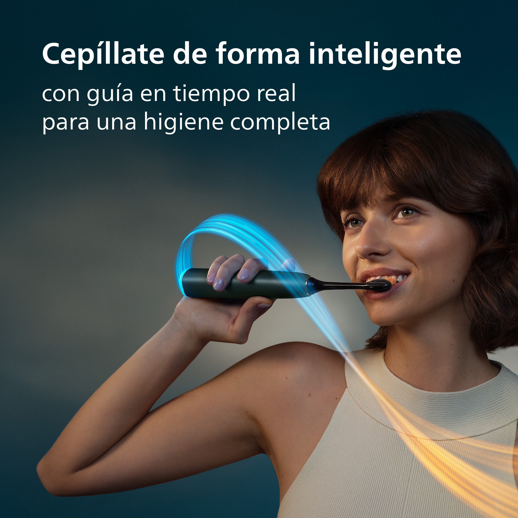 Una mujer sonríe mientras se cepilla los dientes con un cepillo eléctrico oscuro con luz azul.