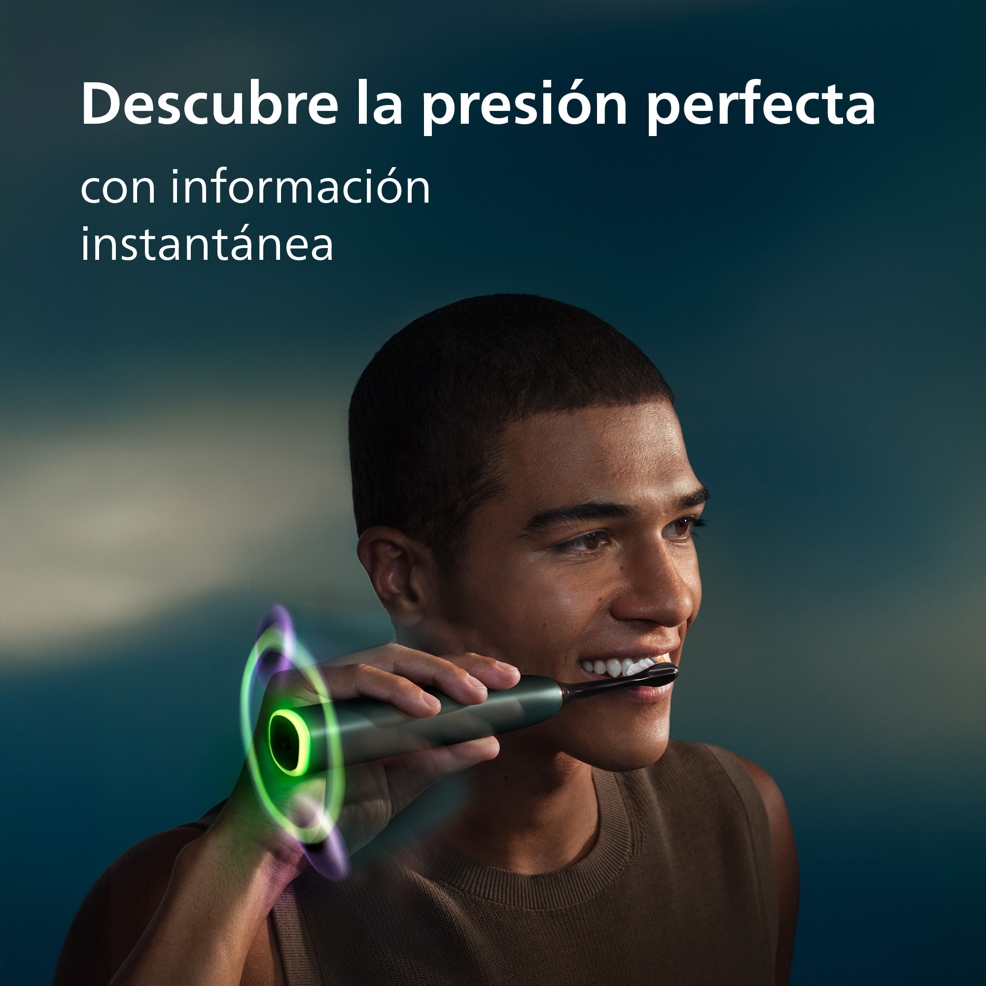 Un hombre sonríe mientras usa un cepillo de dientes eléctrico con luz verde.