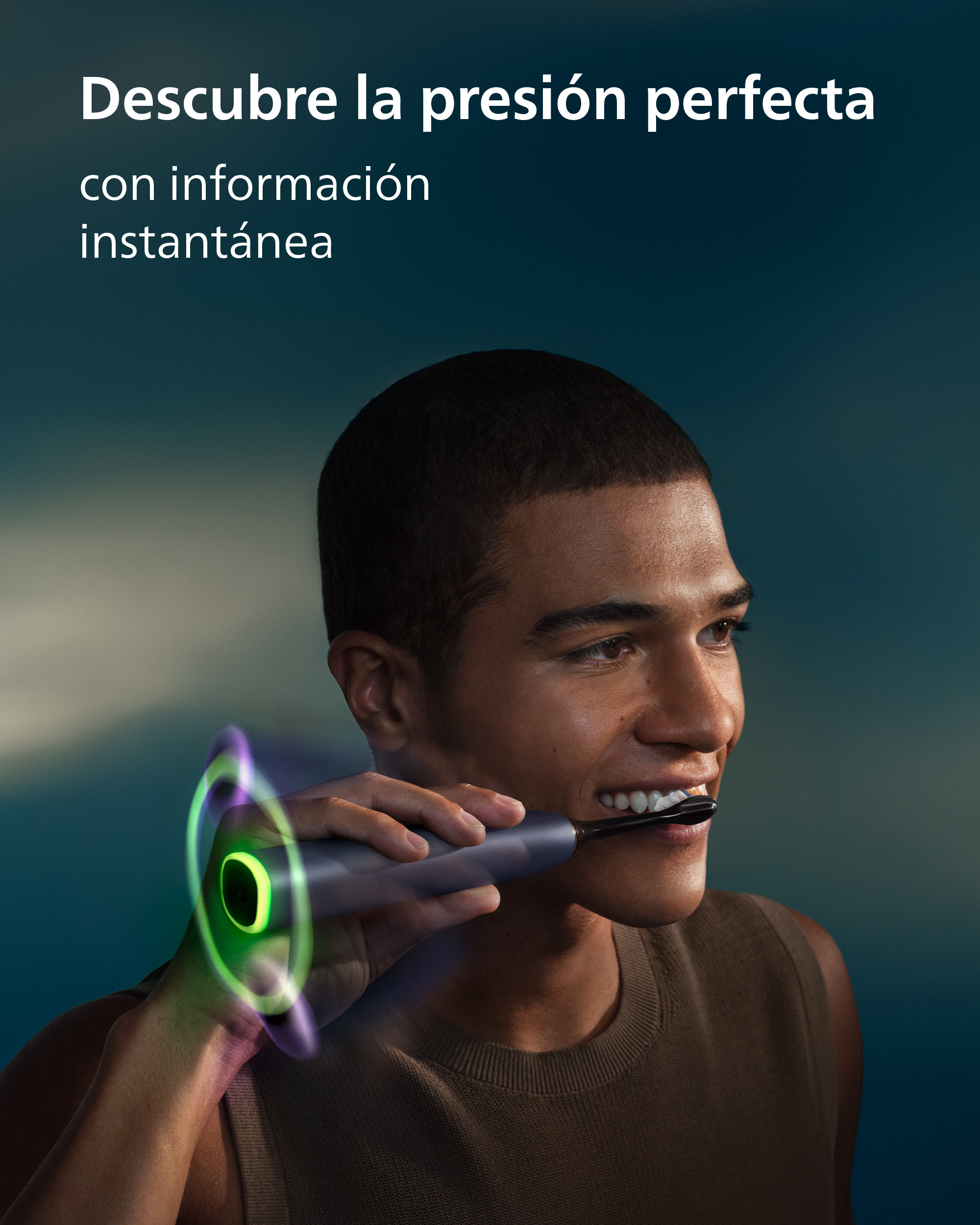 Un hombre sonríe mientras se cepilla los dientes con un cepillo eléctrico con un anillo de luz verde.