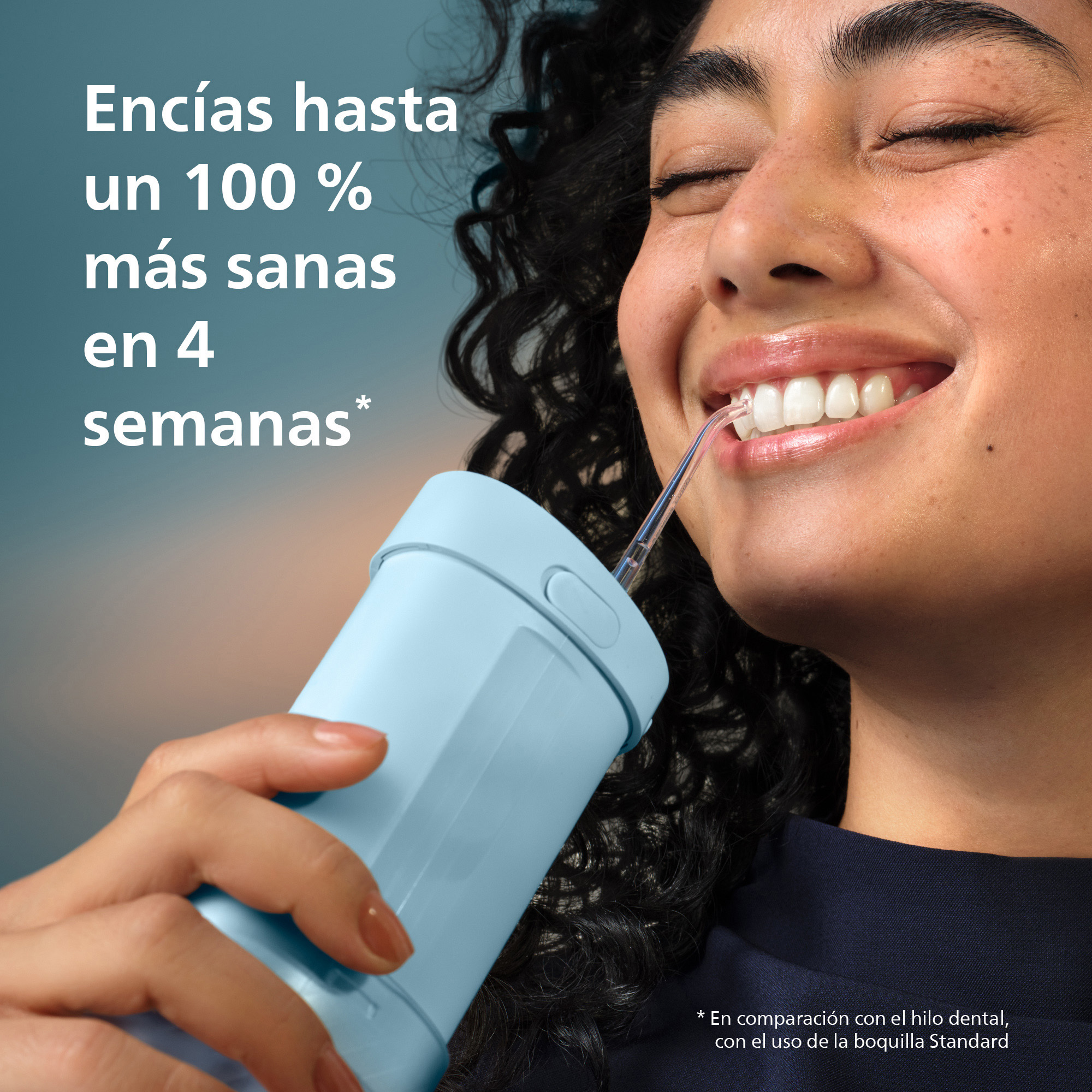 Una mujer sonríe mientras usa un irrigador bucal azul. Se ve texto en español.