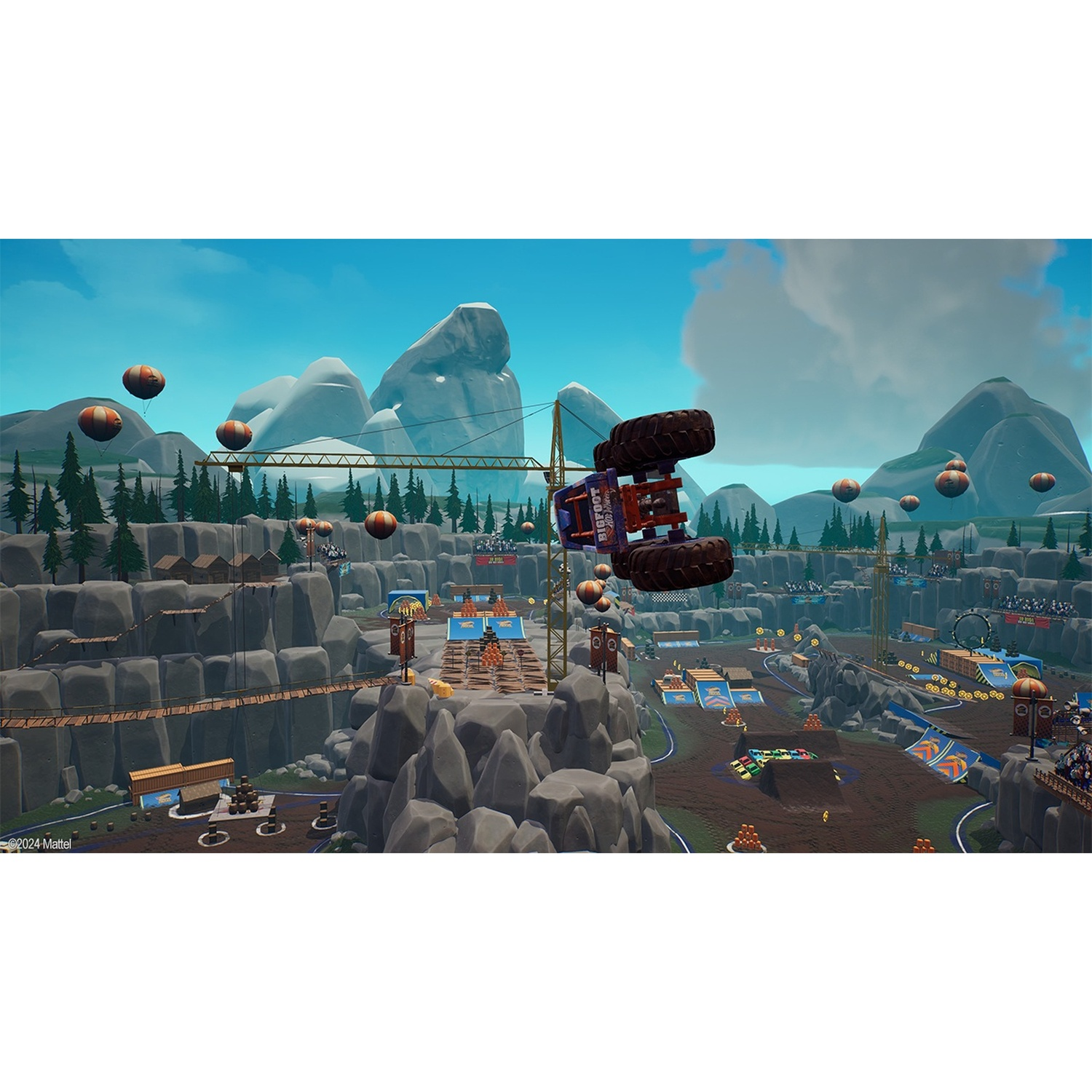 A monster truck performs a jump on a hilly track with mountains in the background.