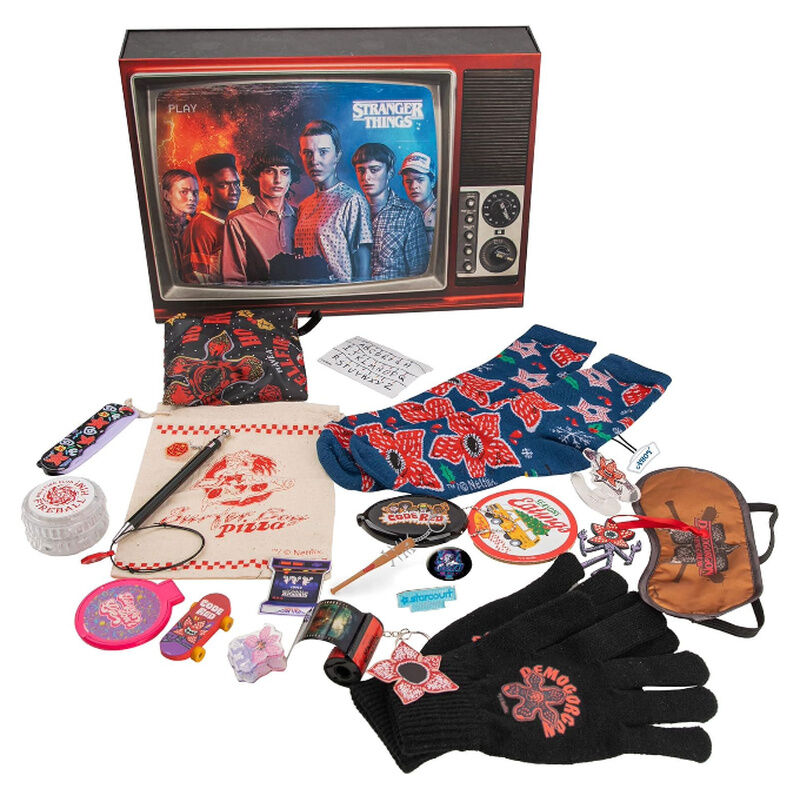 Set de merchandising de Stranger Things sobre fondo blanco que incluye caja, calcetines, guantes y accesorios.