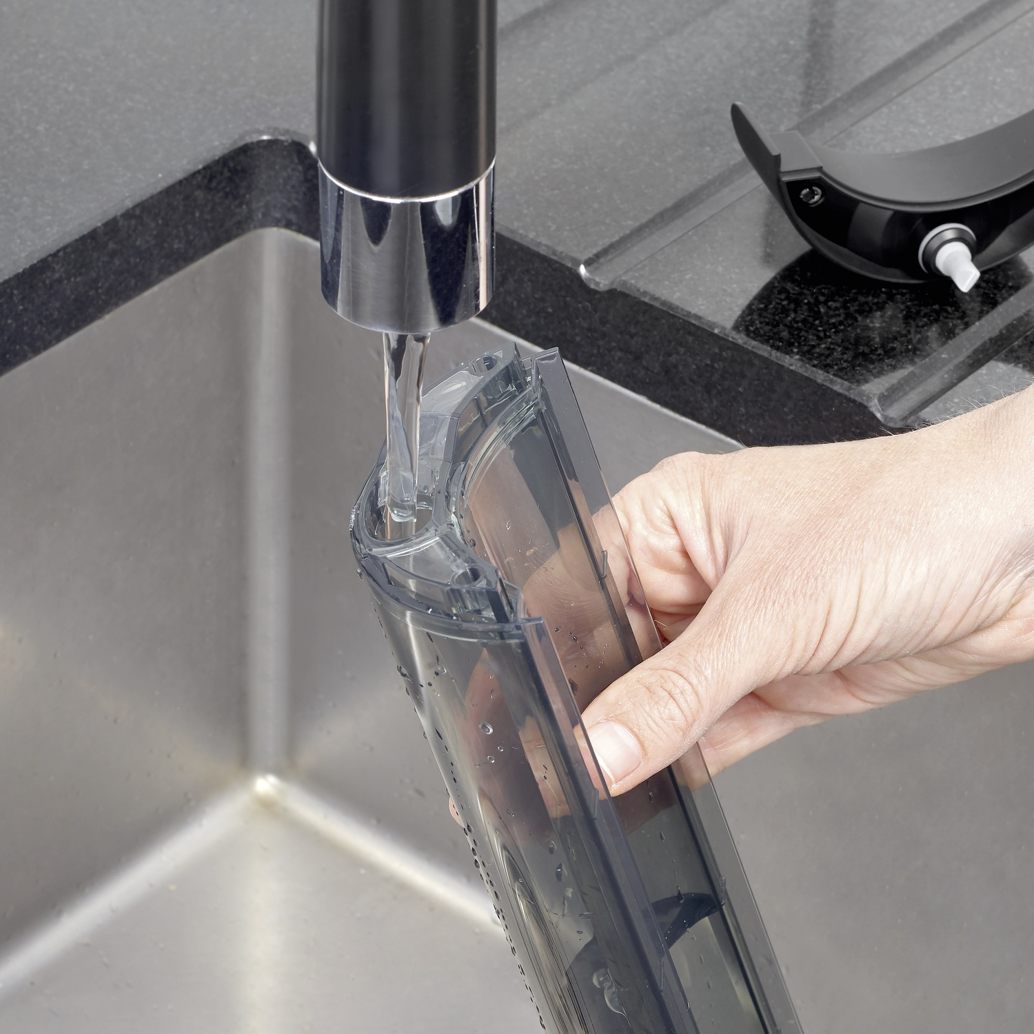 Una mano tiene un contenitore di plastica trasparente sotto il rubinetto di un lavandino.