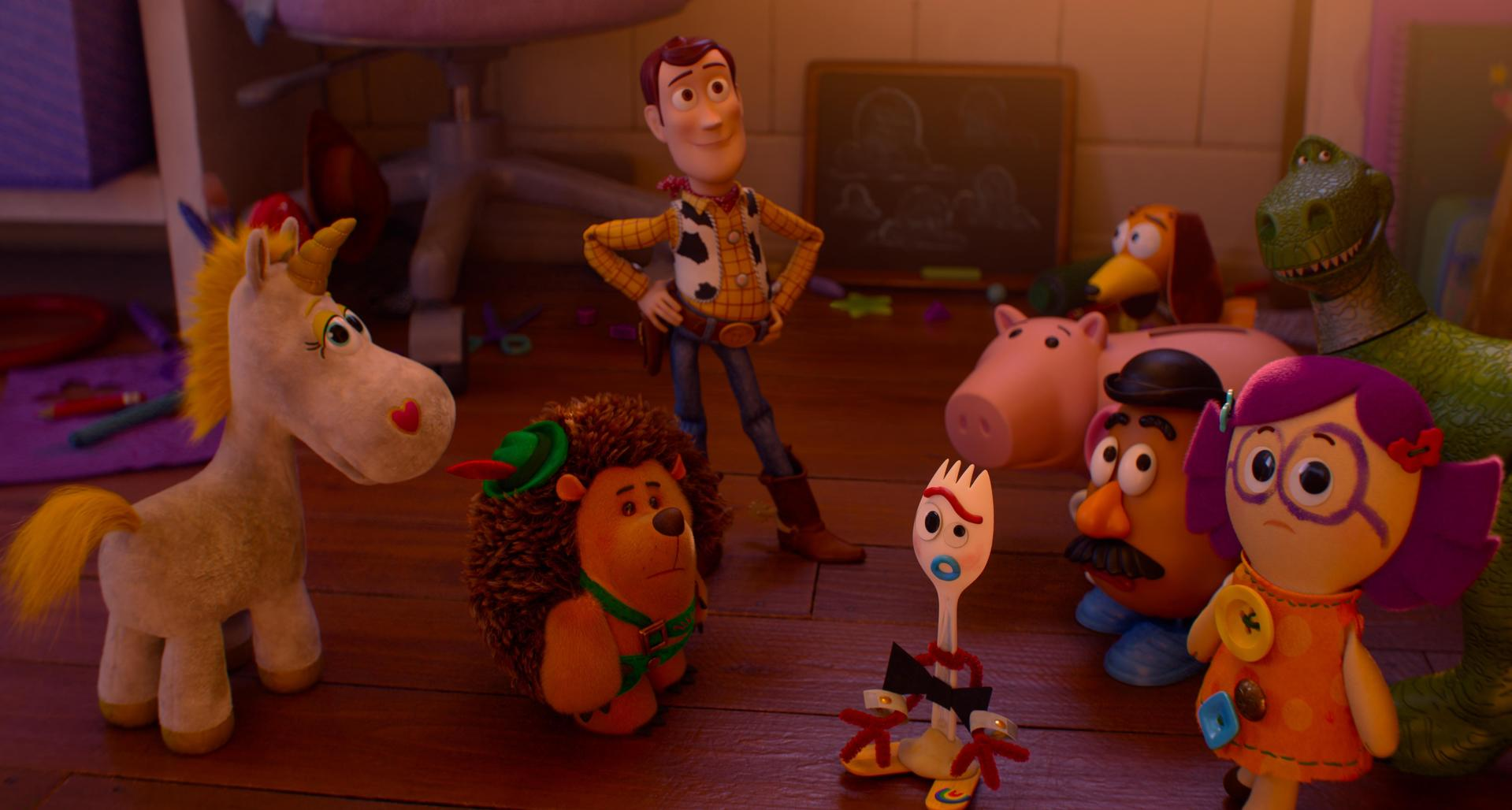 Spielzeugfiguren wie Woody, Forky und Rex stehen auf einem Holzfussboden in einem Kinderzimmer.