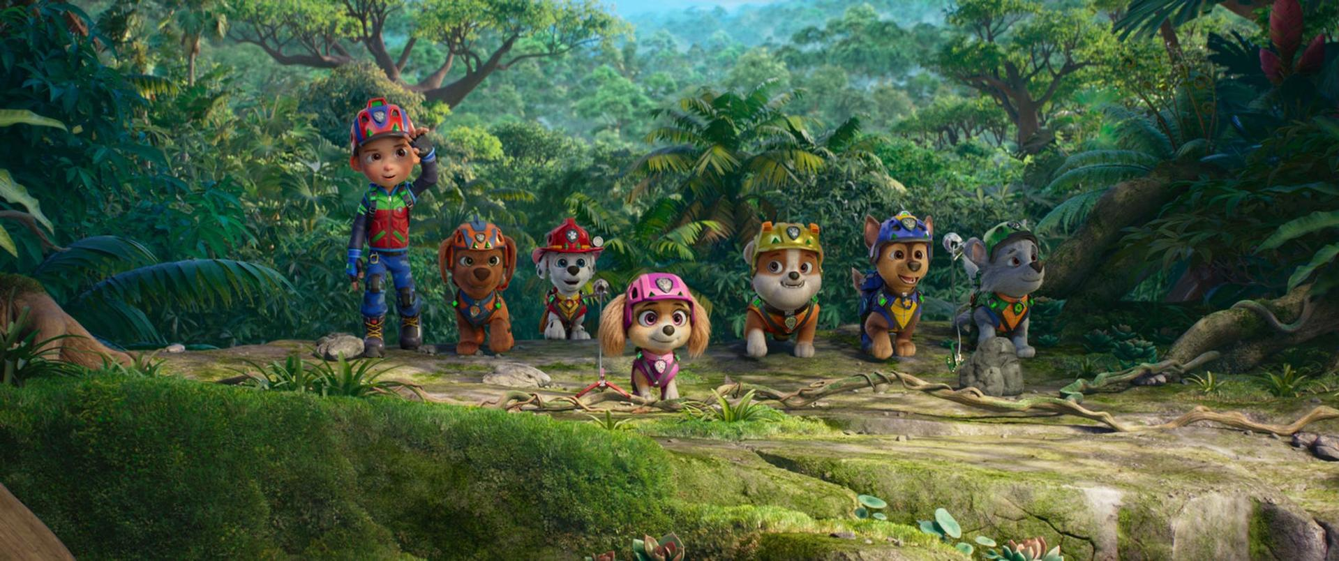 Ryder und sechs Paw Patrol Welpen in Rettungsausrüstung stehen zusammen im tropischen Dschungel.