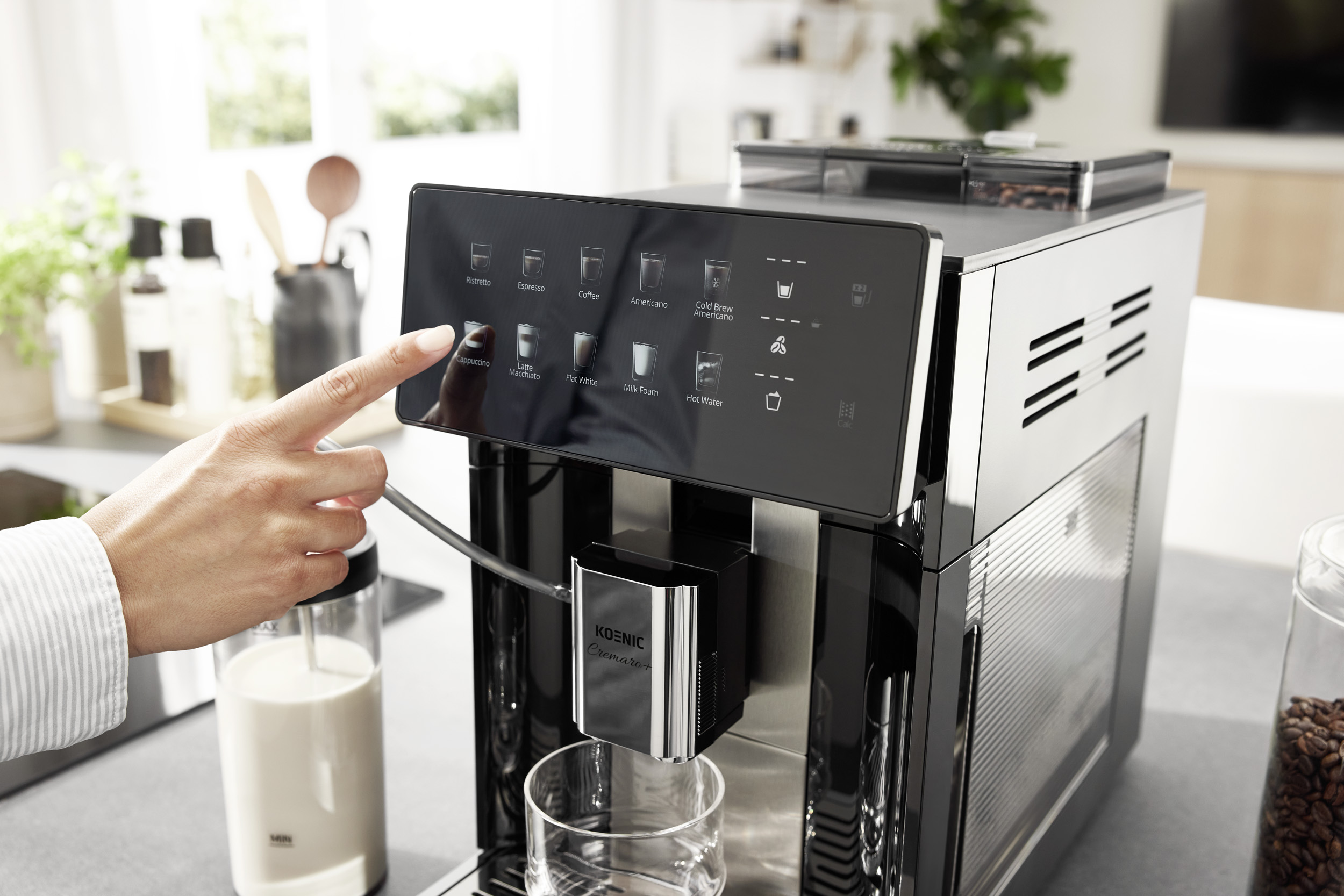 Eine Hand tippt auf das Touch-Display eines modernen schwarzen Kaffeevollautomaten in einer Küche.