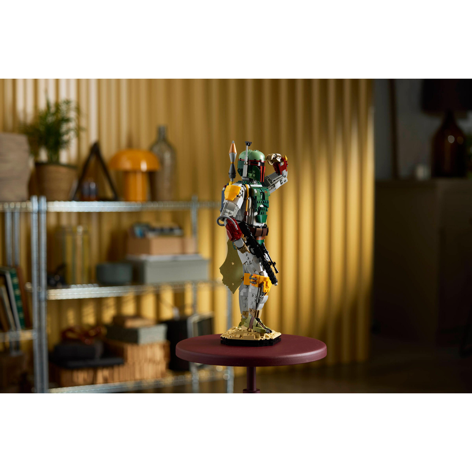 Una statuetta Lego di Boba Fett è su un piccolo tavolo davanti a uno scaffale.