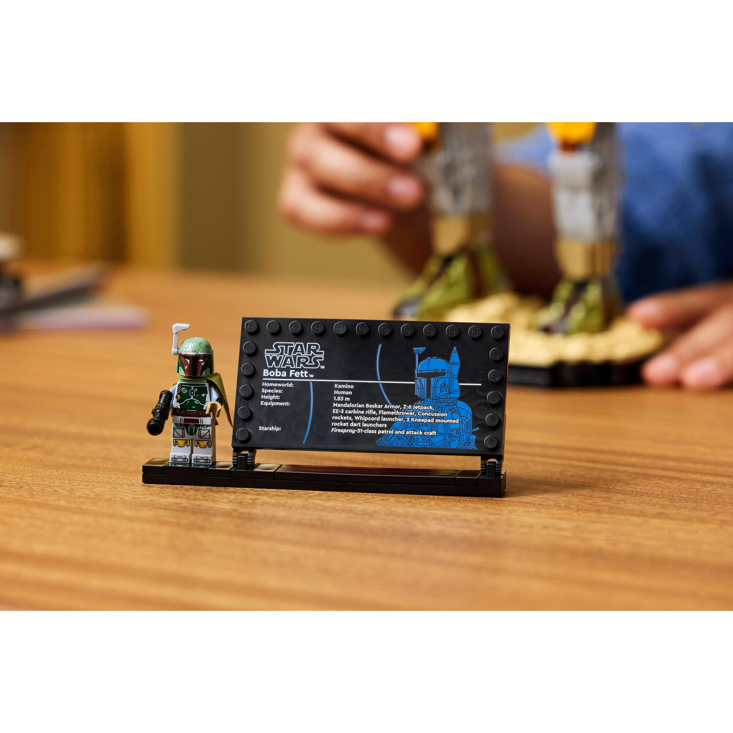 Minifigure Lego di Boba Fett con targa informativa su un tavolo di legno, sfondo sfocato.