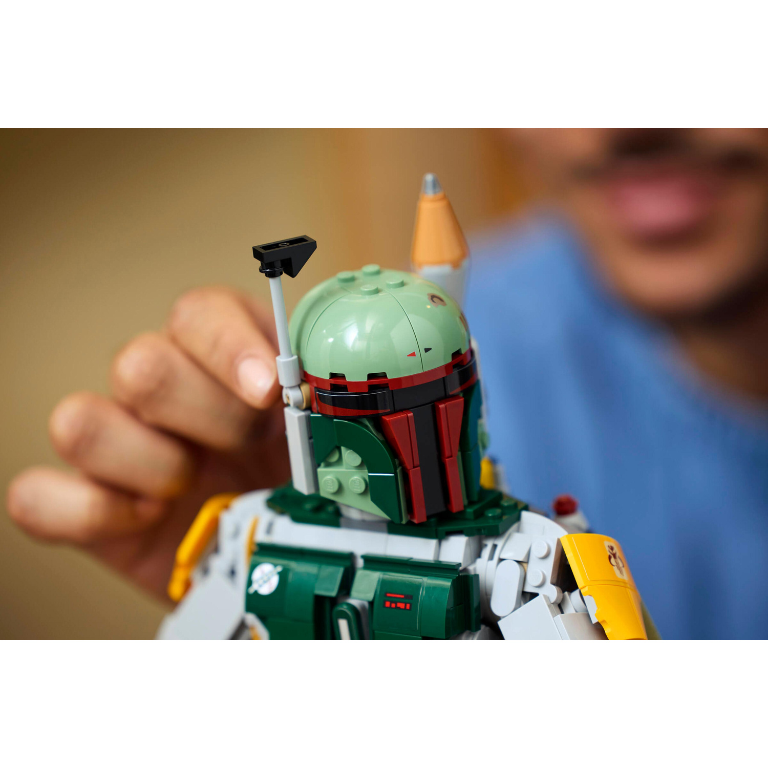 Una persona costruisce una minifigure verde Lego di Boba Fett con elmo e armatura.