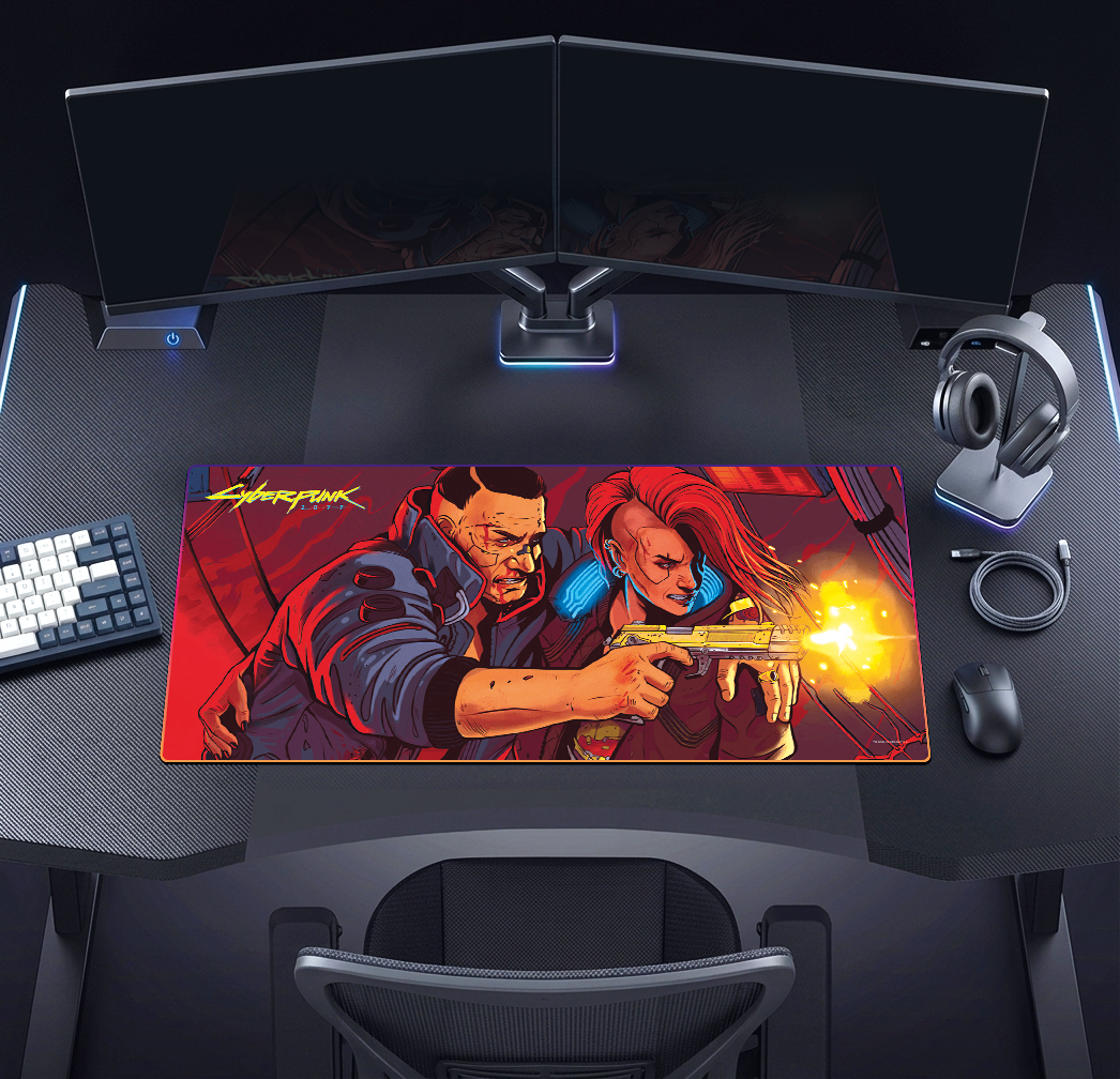 Játékíróasztal két monitorral, billentyűzettel, egérrel és egy Cyberpunk egérpaddal.