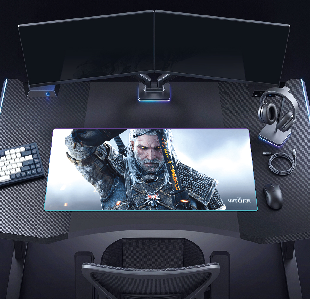 Játékos íróasztal két monitorral, billentyűzettel, egérrel, fejhallgatóval és Witcher egérpaddal.