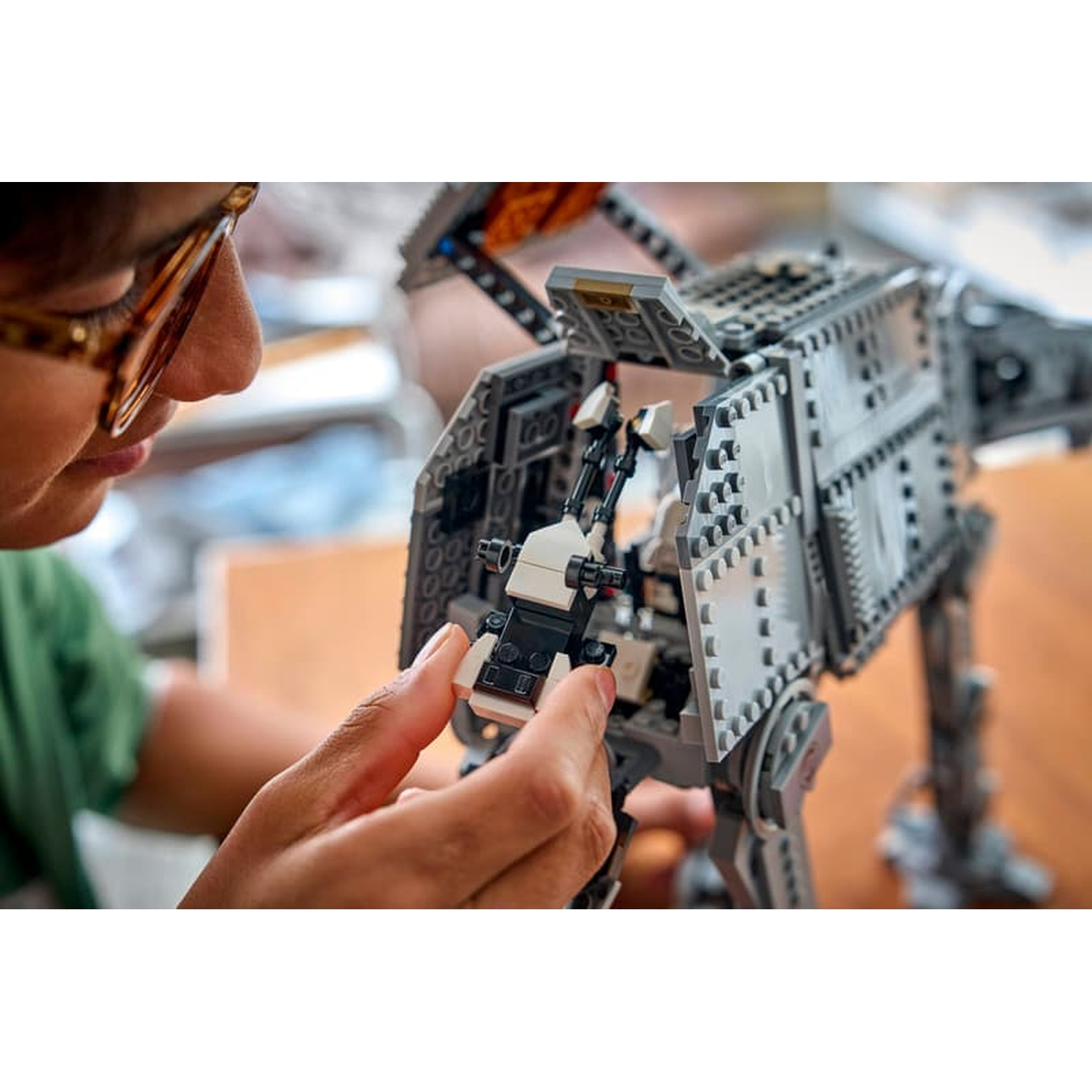 Una persona assembla un camminatore Lego Star Wars AT-ST grigio, tenendo un piccolo componente interno.