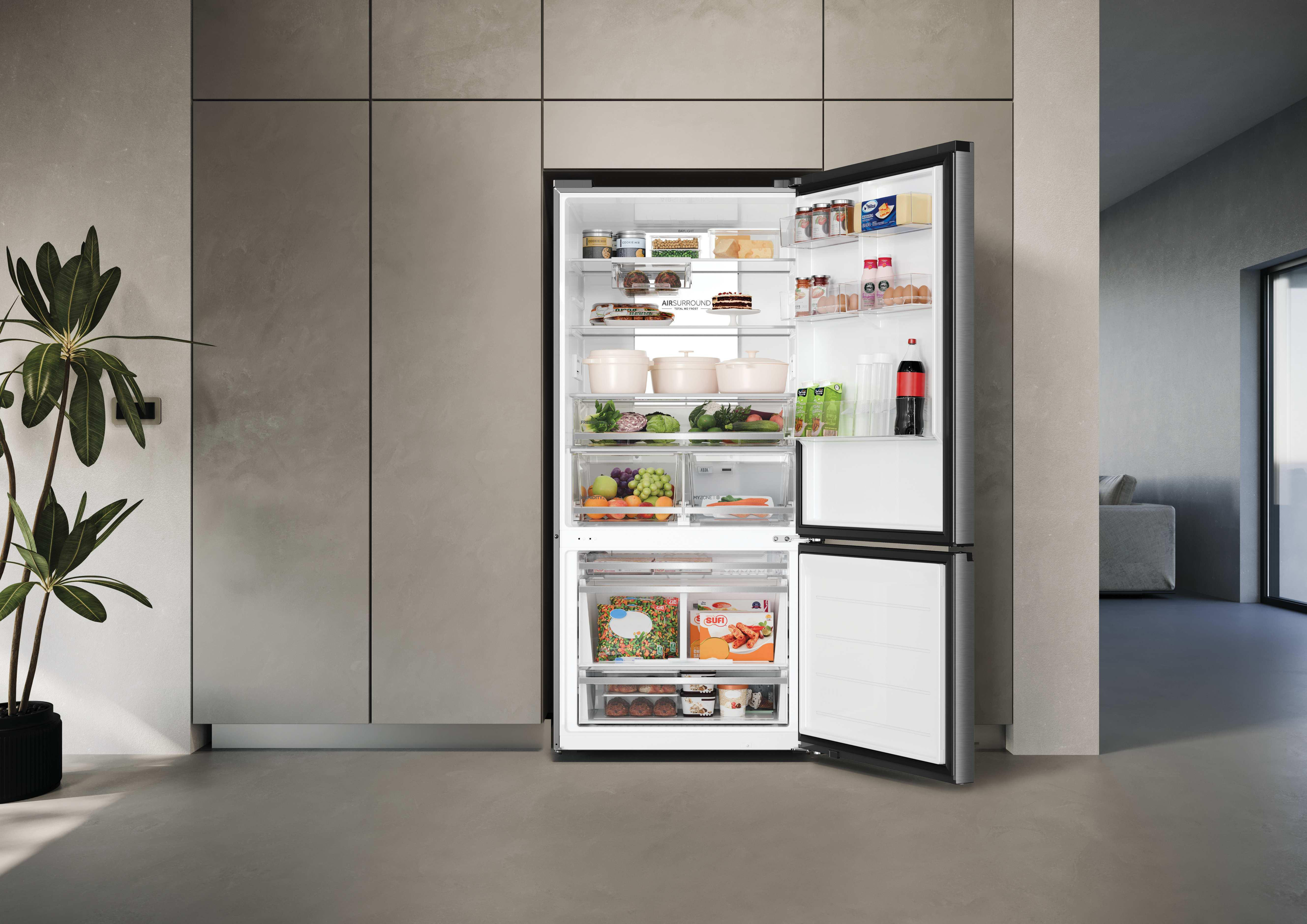Ein offener, vollmöblierter Kühlschrank in einer modernen Küche mit Lebensmitteln auf den Regalen und in den Fächern.