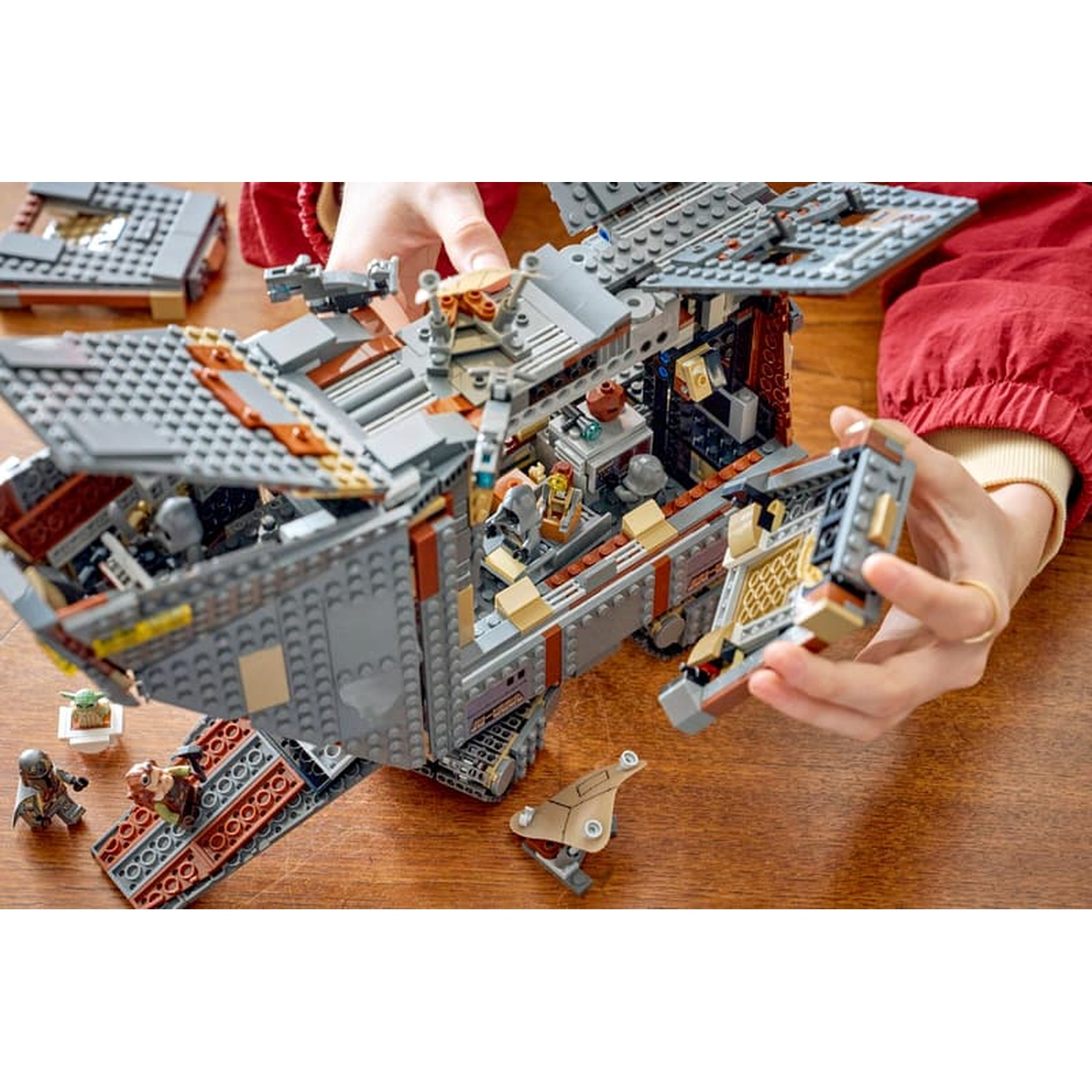 Persona costruisce una grande astronave LEGO con interni aperti e minifigure.