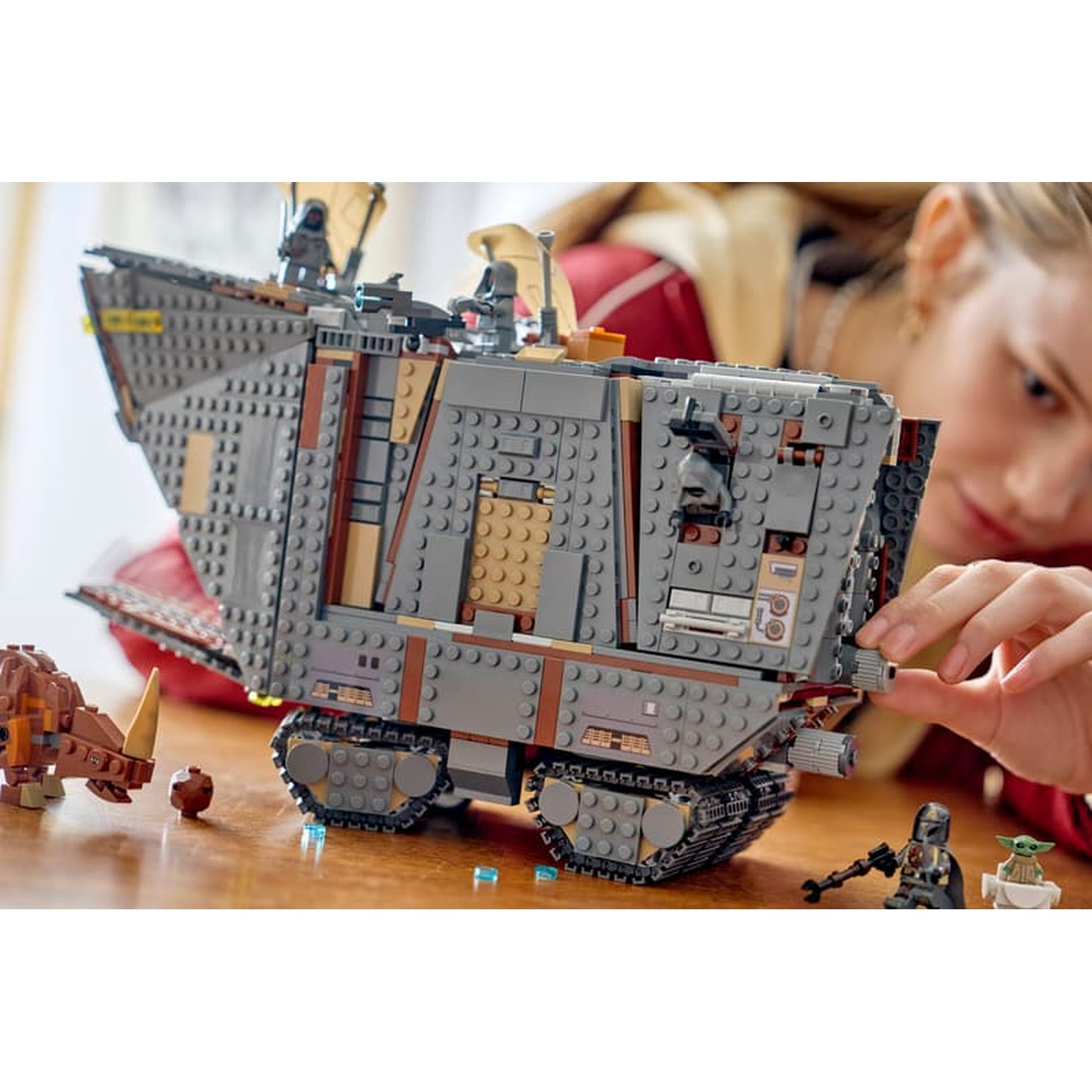 Una persona costruisce un grande trasporto corazzato LEGO Star Wars, con minifigure.