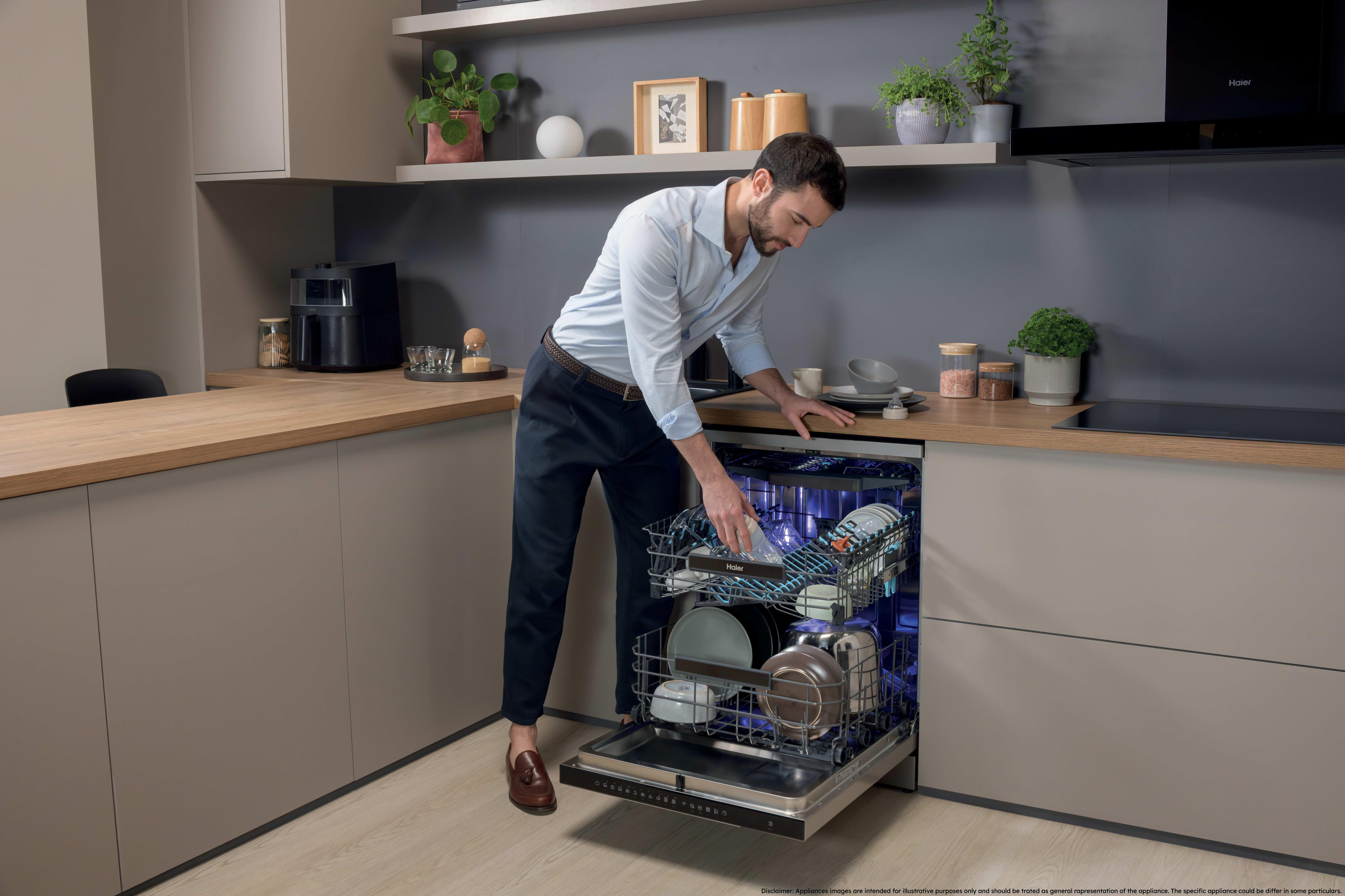 Ein Mann im hellblauen Hemd öffnet die Spülmaschine in einer modernen Küche mit Holzarbeitsplatten.