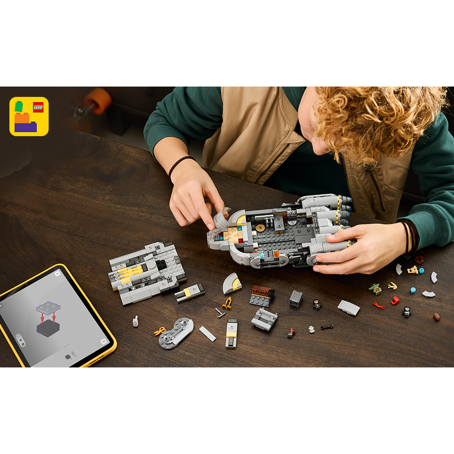 Una persona costruisce una nave spaziale Lego grigia su un tavolo.