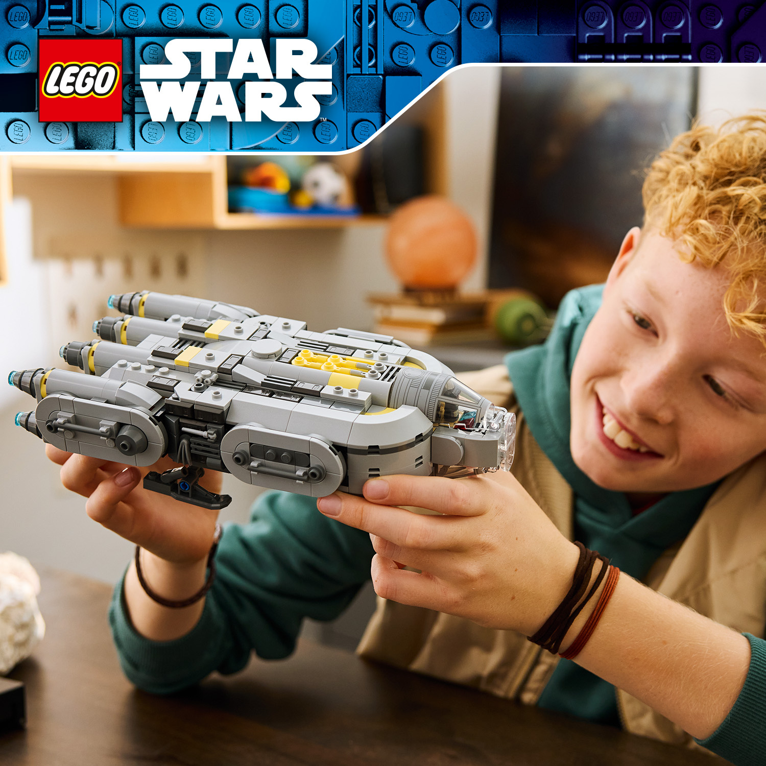Un ragazzo tiene orgogliosamente in mano una navicella spaziale grigia LEGO Star Wars.