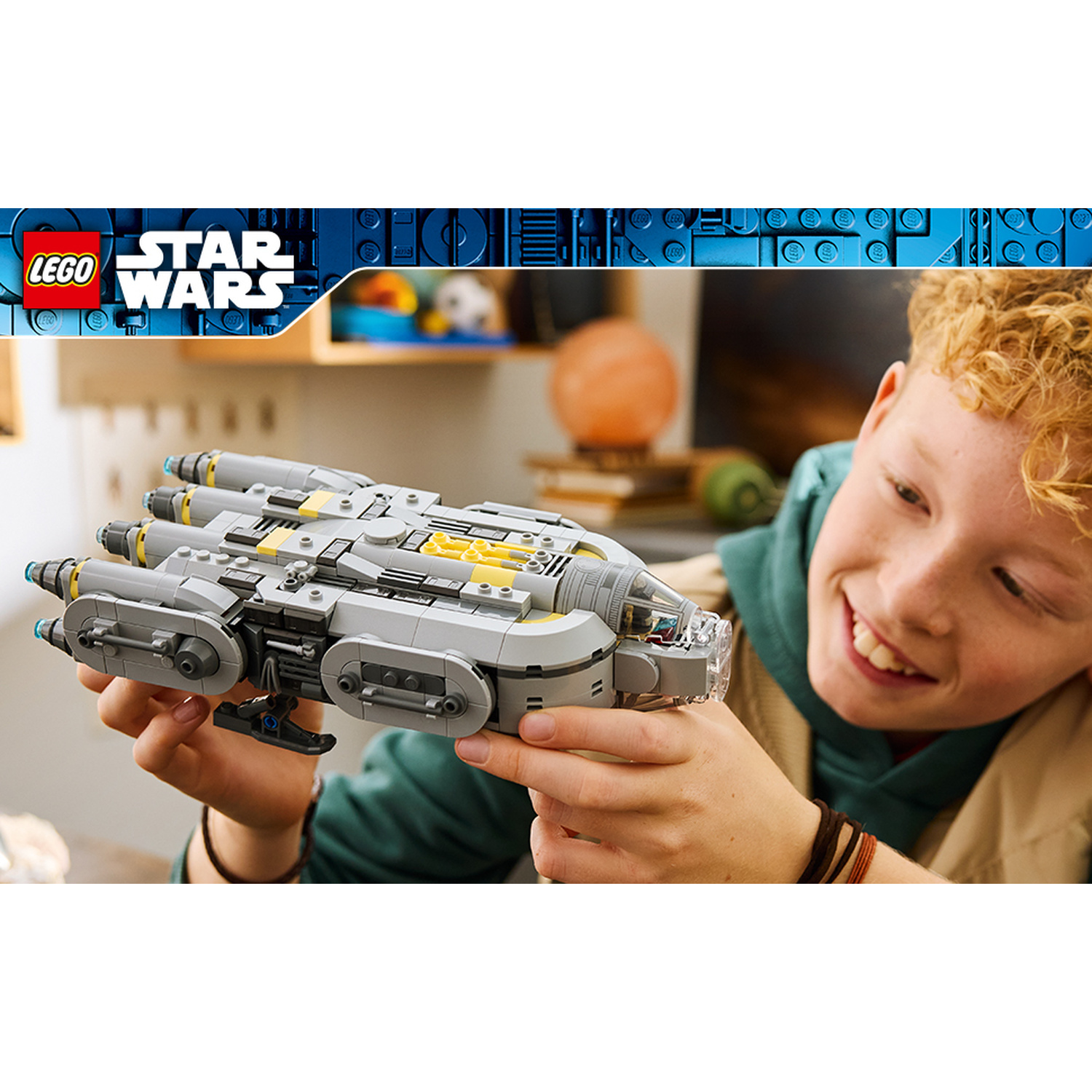 Un ragazzo sorride mentre tiene in mano un modello di astronave Lego Star Wars.