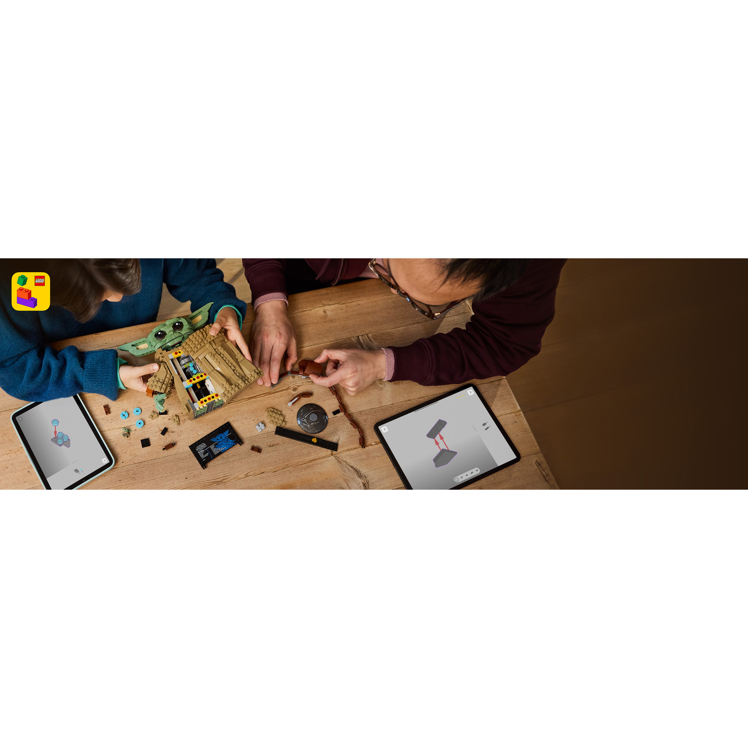 Un bambino e un adulto costruiscono Lego insieme, guidati da istruzioni digitali su tablet.
