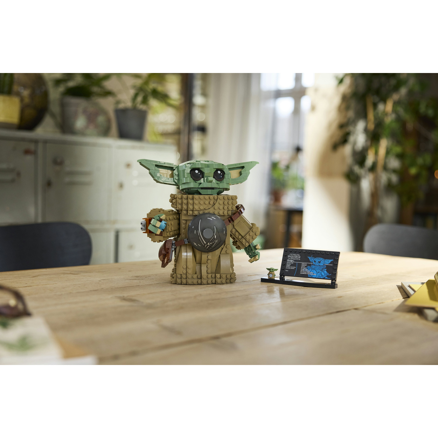 Figura Lego di Grogu su tavolo in legno con targa e minifigura.