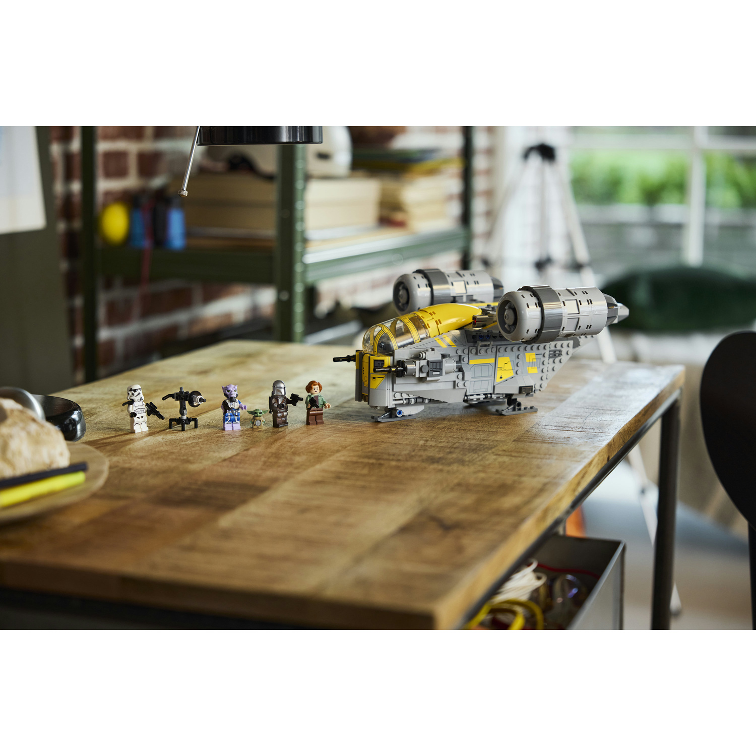 Modello di astronave Lego Star Wars Razor Crest e minifigure su una scrivania di legno.