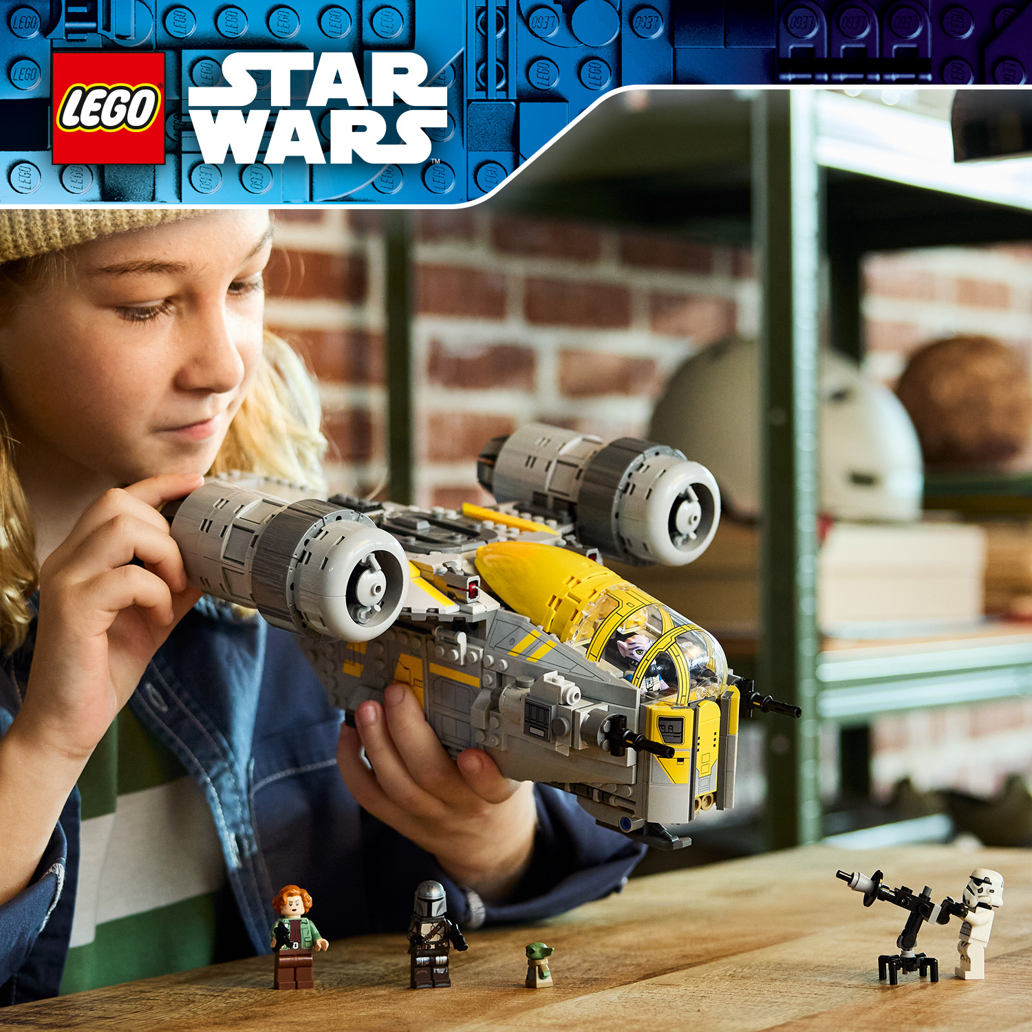 Un bambino tiene una nave spaziale LEGO Star Wars, con minifigure su un tavolo di legno in primo piano.