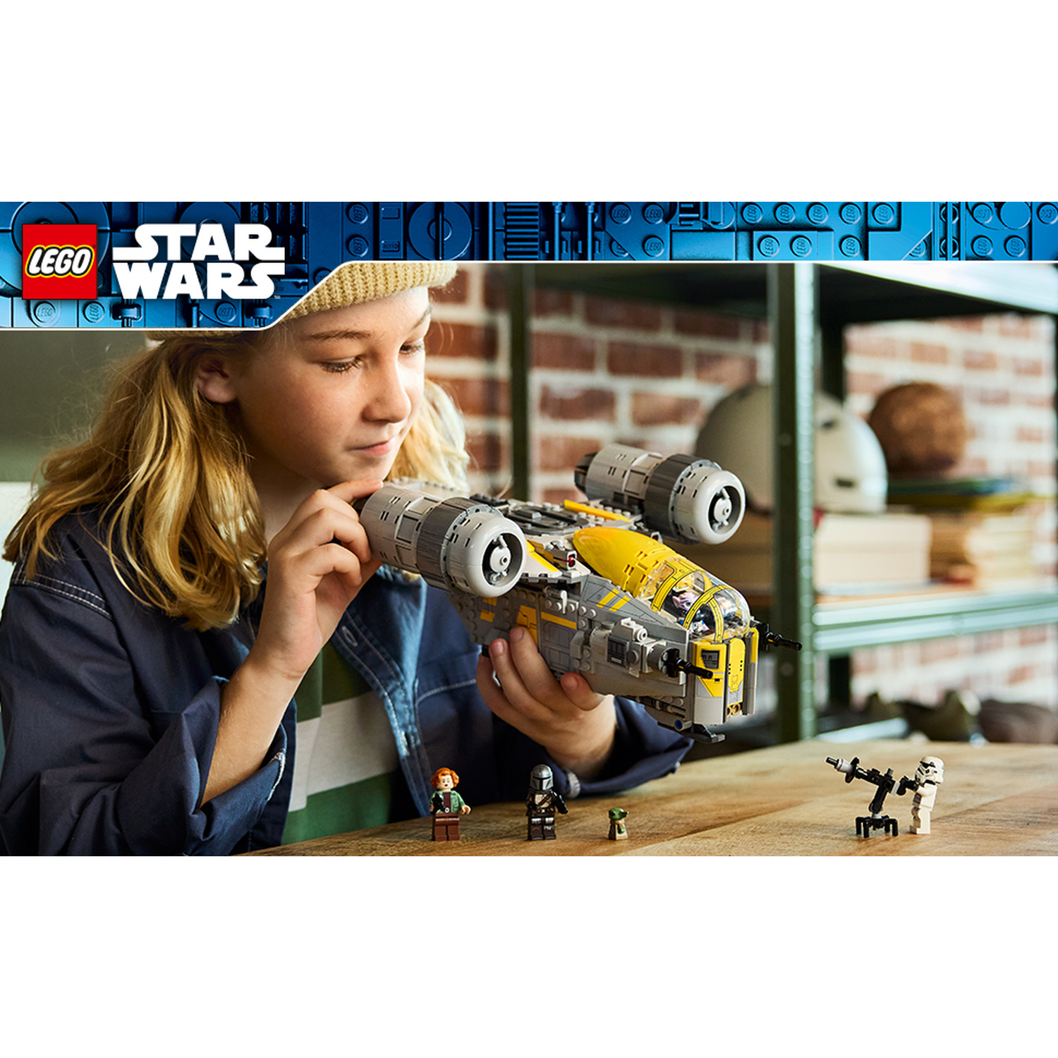 Un bambino costruisce un'astronave Lego Star Wars con minifigure su un tavolo.