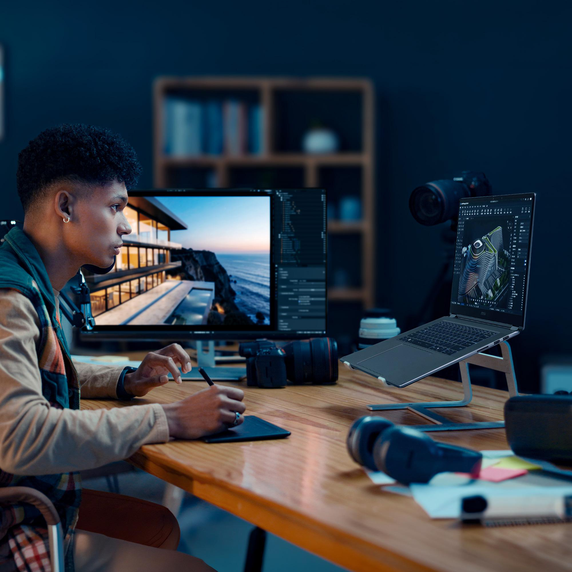 Ein Mann bearbeitet Fotos an Laptop und Monitor und nutzt ein Grafiktablett an seinem Holztisch im Studio.