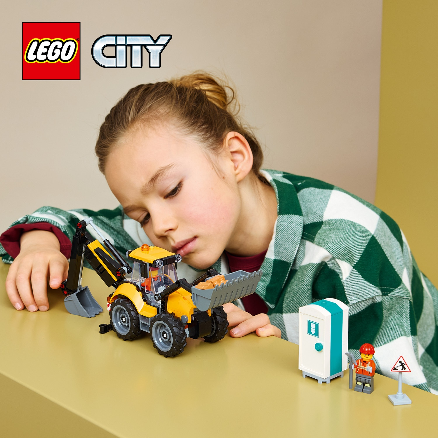 Una ragazza con camicia a quadri verde guarda una ruspa giocattolo Lego City, un bagno portatile e una minifigura.