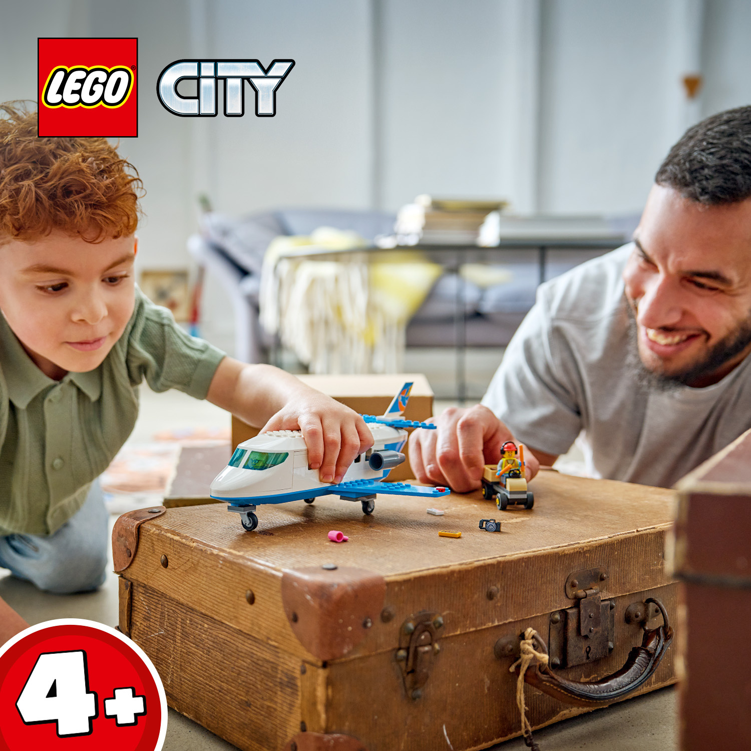 Un bambino e un uomo giocano con i giocattoli LEGO City su una vecchia valigia.