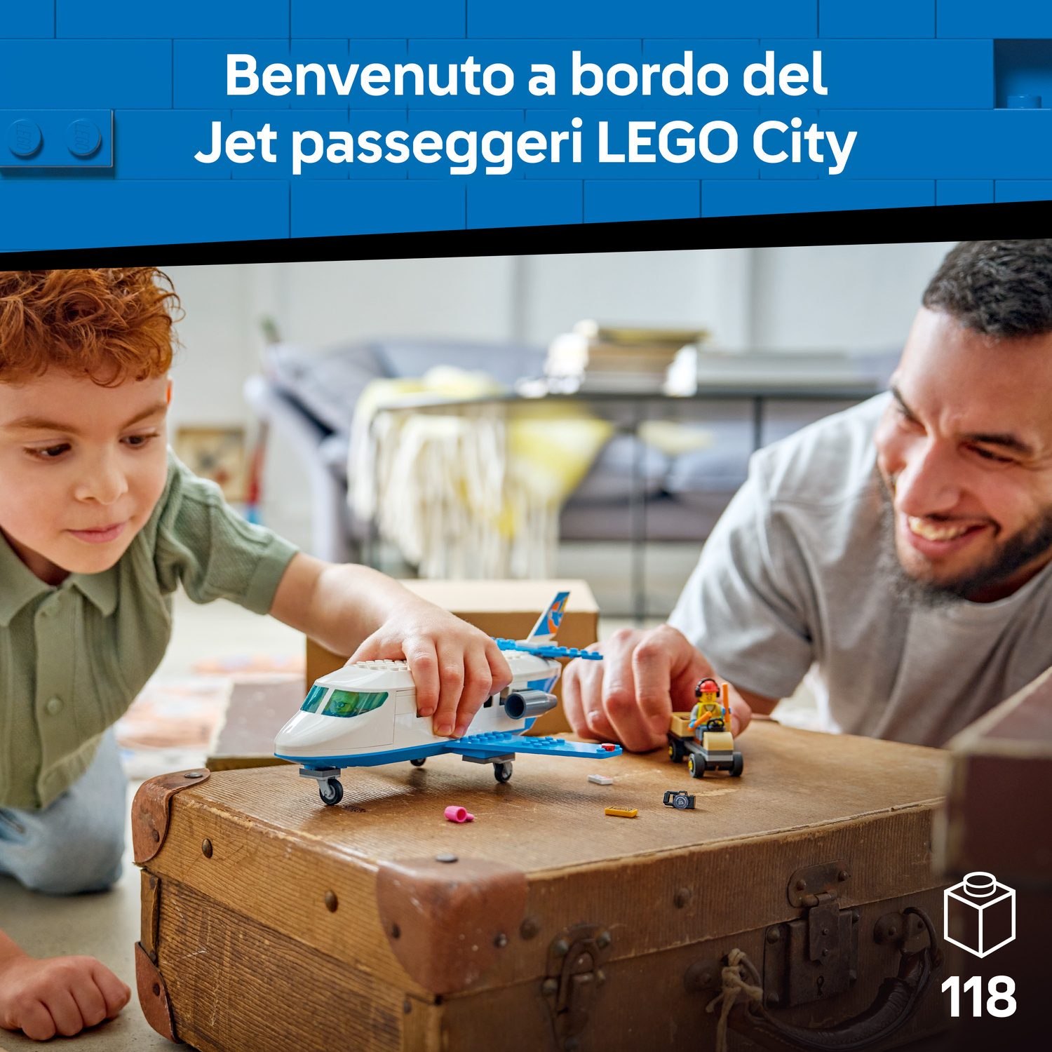 Un bambino e un uomo giocano con un aereo Lego sopra una vecchia valigia.