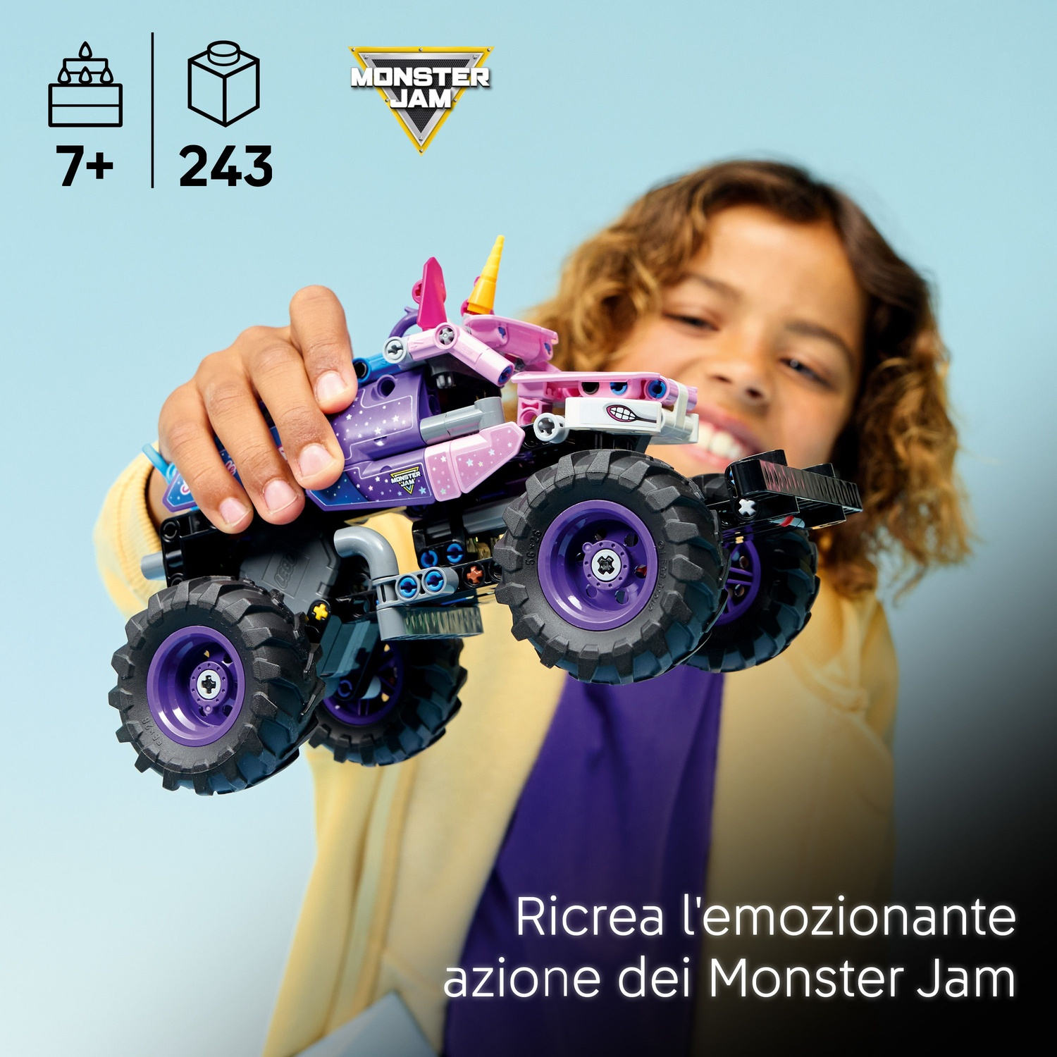 Un bambino solleva un camion Lego Monster Jam rosa e viola con grandi pneumatici su sfondo blu.