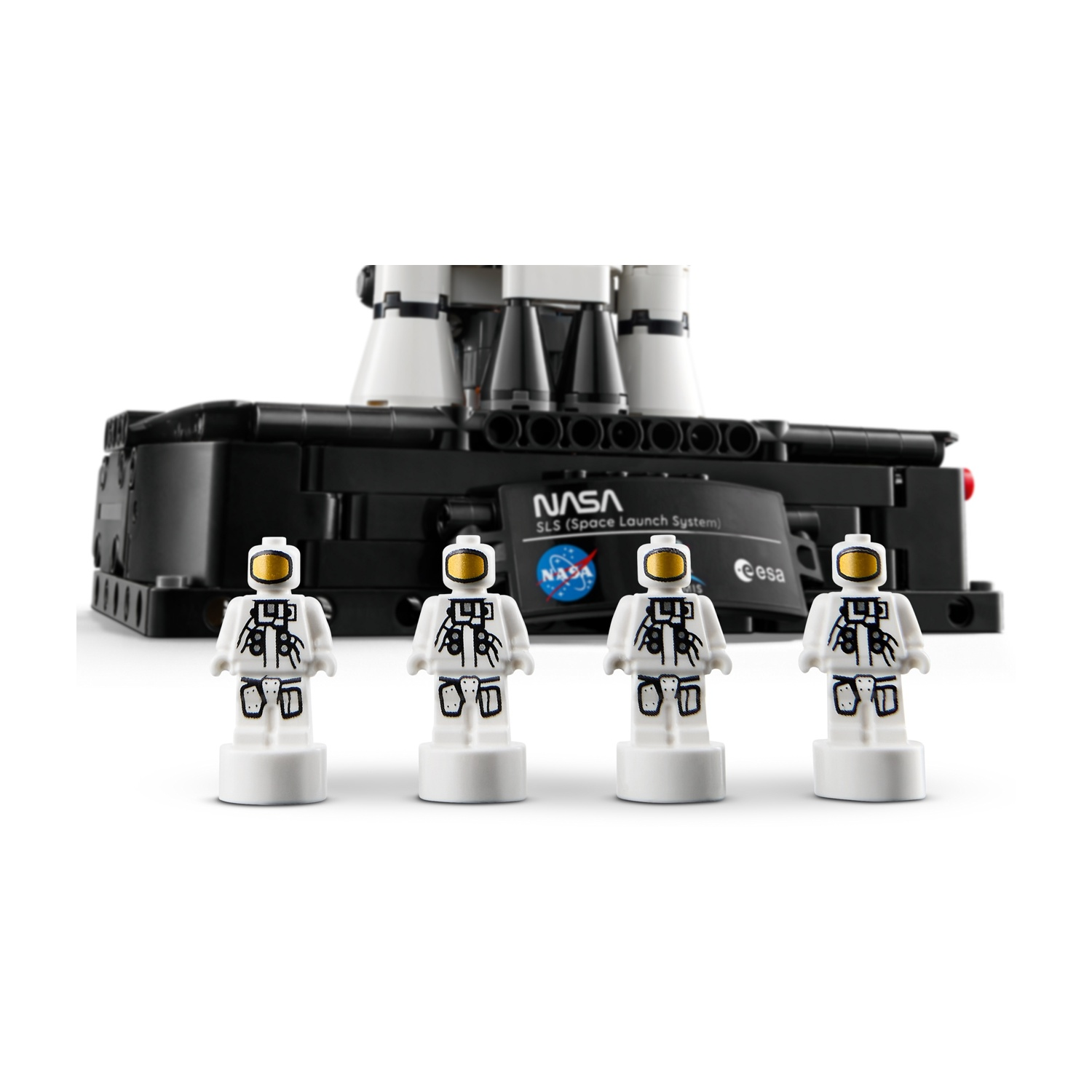 Quattro statuette di astronauti Lego sono in fila davanti a una base nera Lego con logo NASA e razzi.