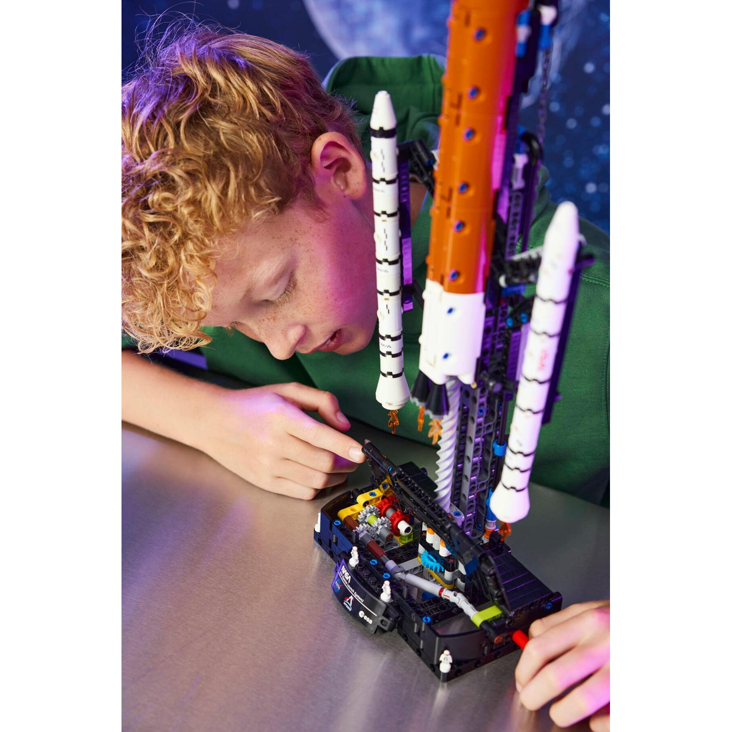 Un ragazzo sta costruendo un grande modello di un razzo spaziale arancione e bianco in Lego.